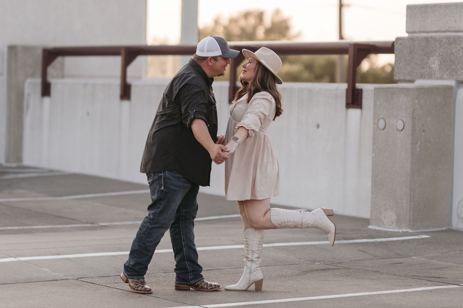 Couple in casual attire sharing a romantic moment in a parking structure at sunset.