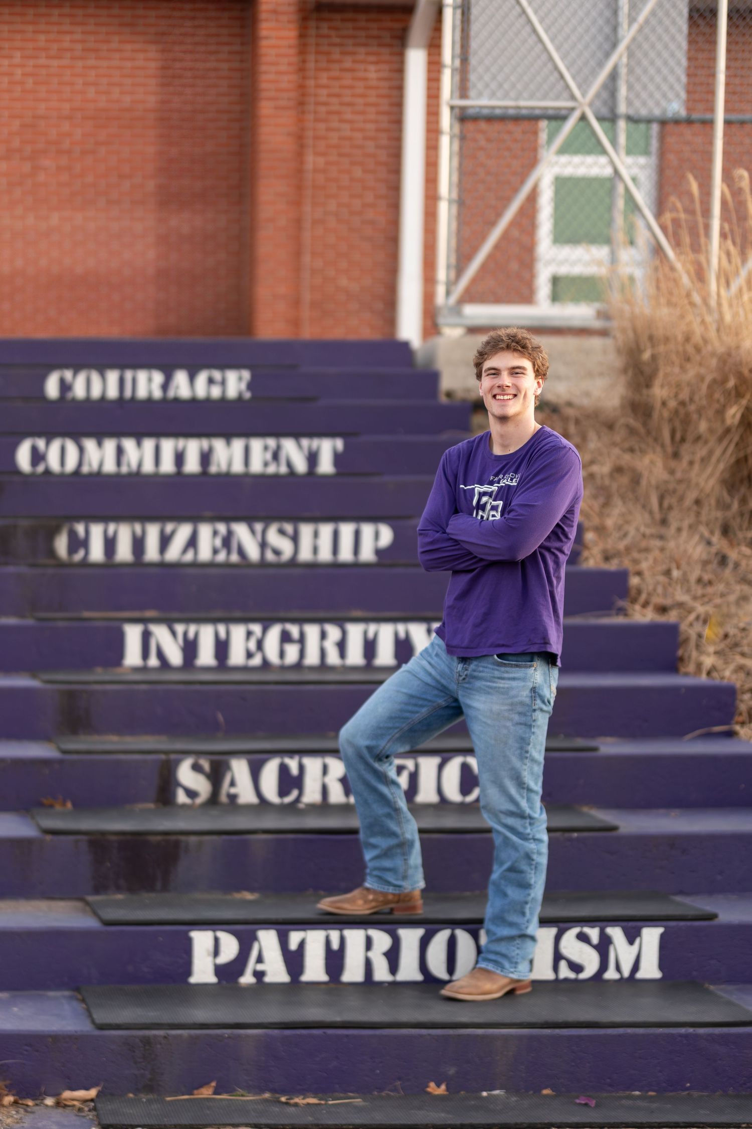 Student stands on purple stairs with inspirational words painted on each step.