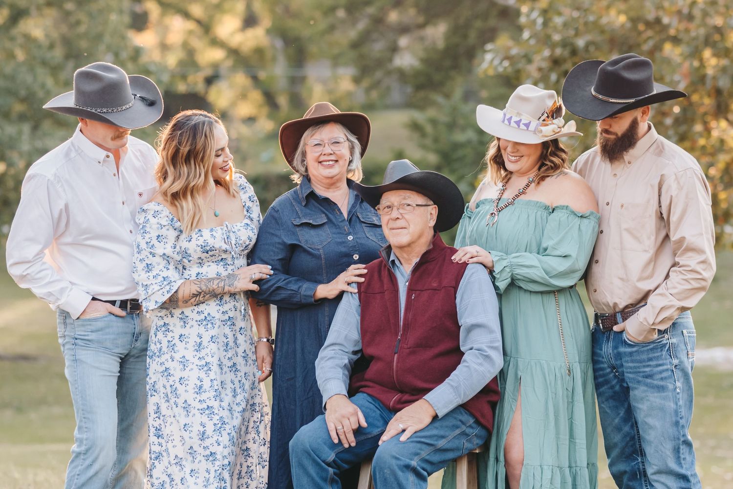 A family group stands together in coordinated western wear during an outdoor photo session.