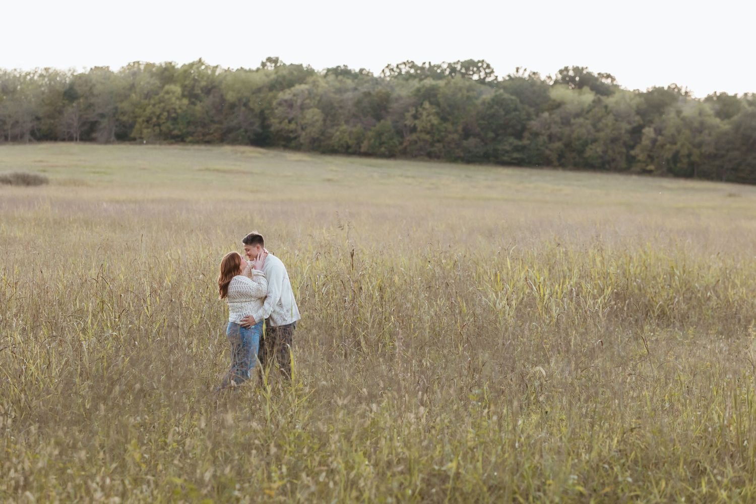 Couple walking together through a golden grass meadow on a sunny afternoon.