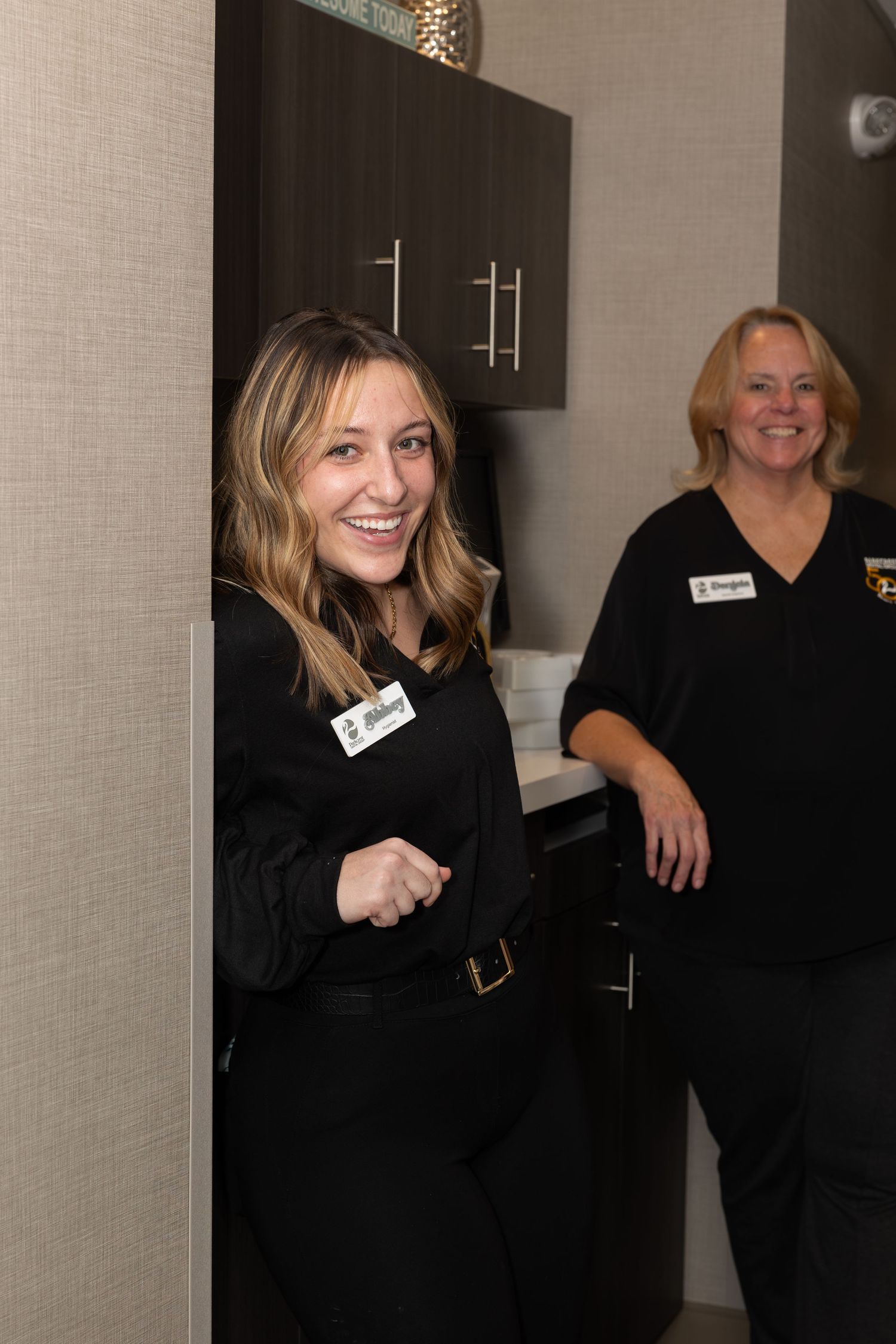 Staff members in black uniforms share cheerful moment in office setting.