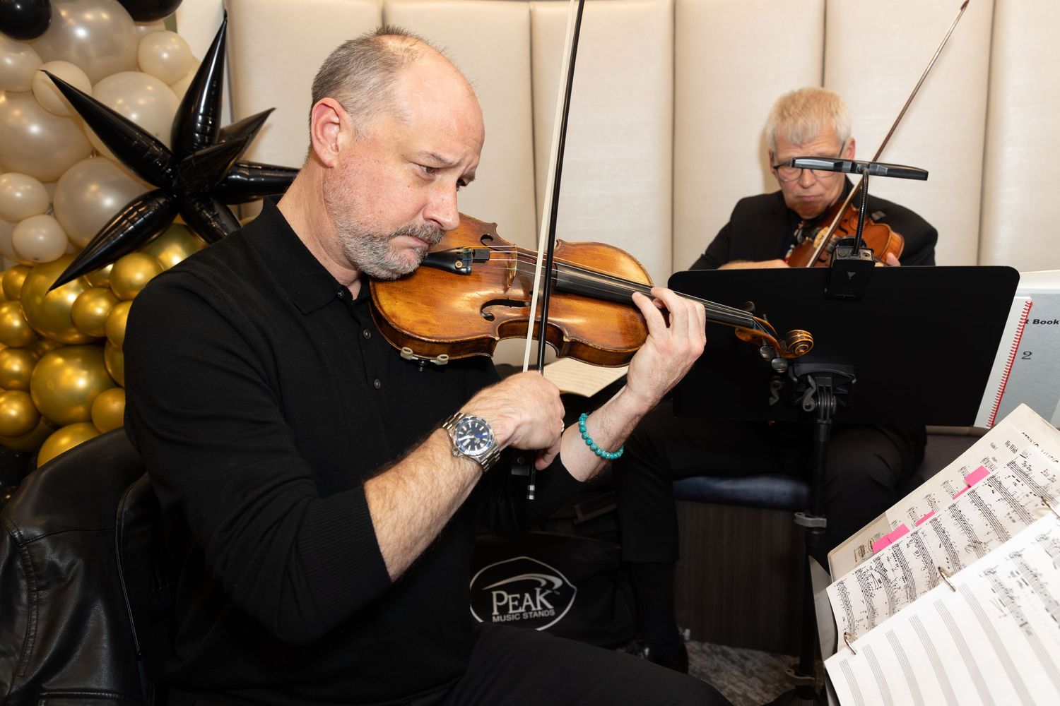 Two musicians playing violins together during an elegant event performance.
