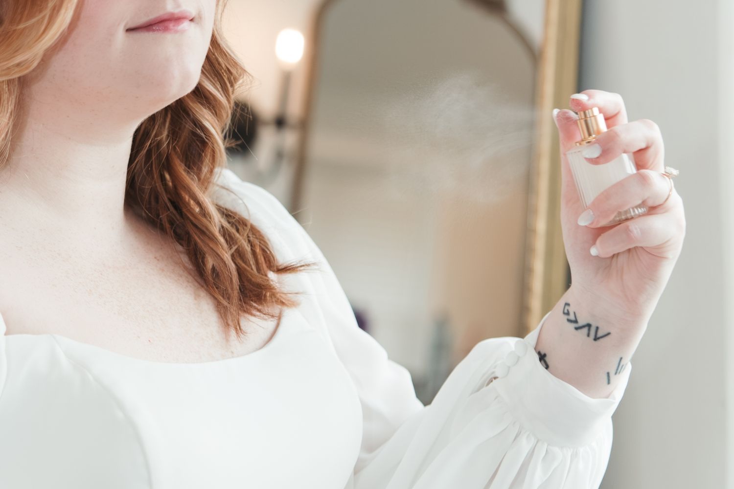 Close-up of a woman's hand and wrist showing a delicate tattoo against a white sleeve.