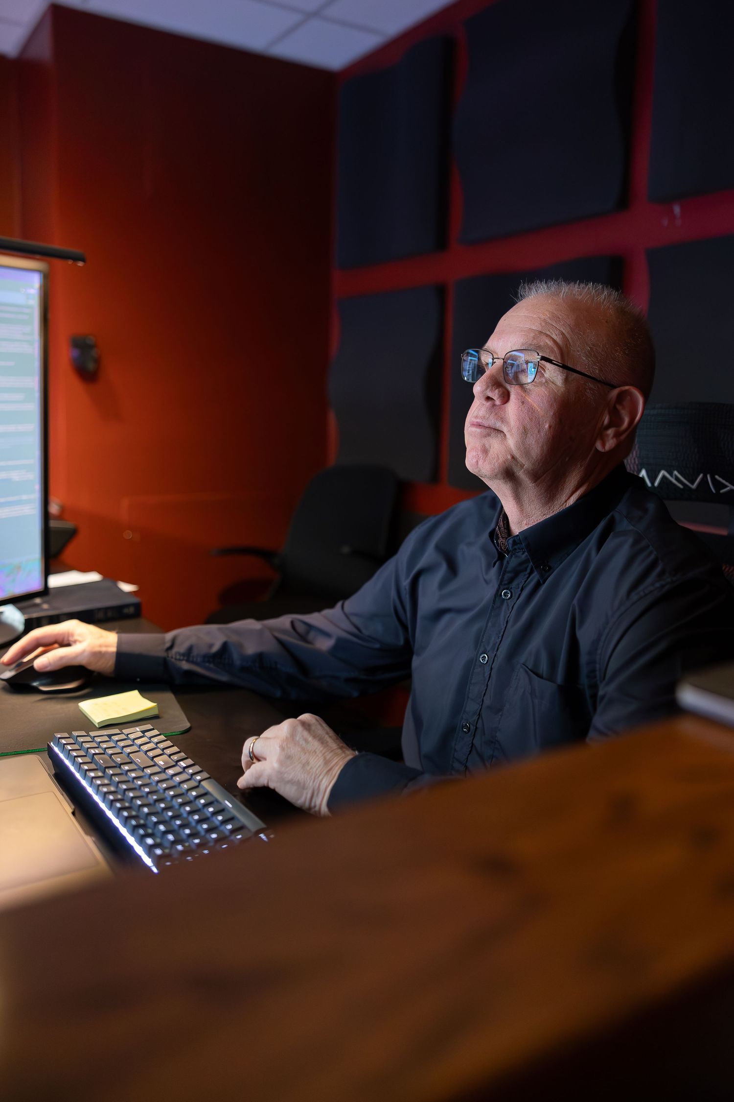 Person working at computer workstation in dark room with orange walls.