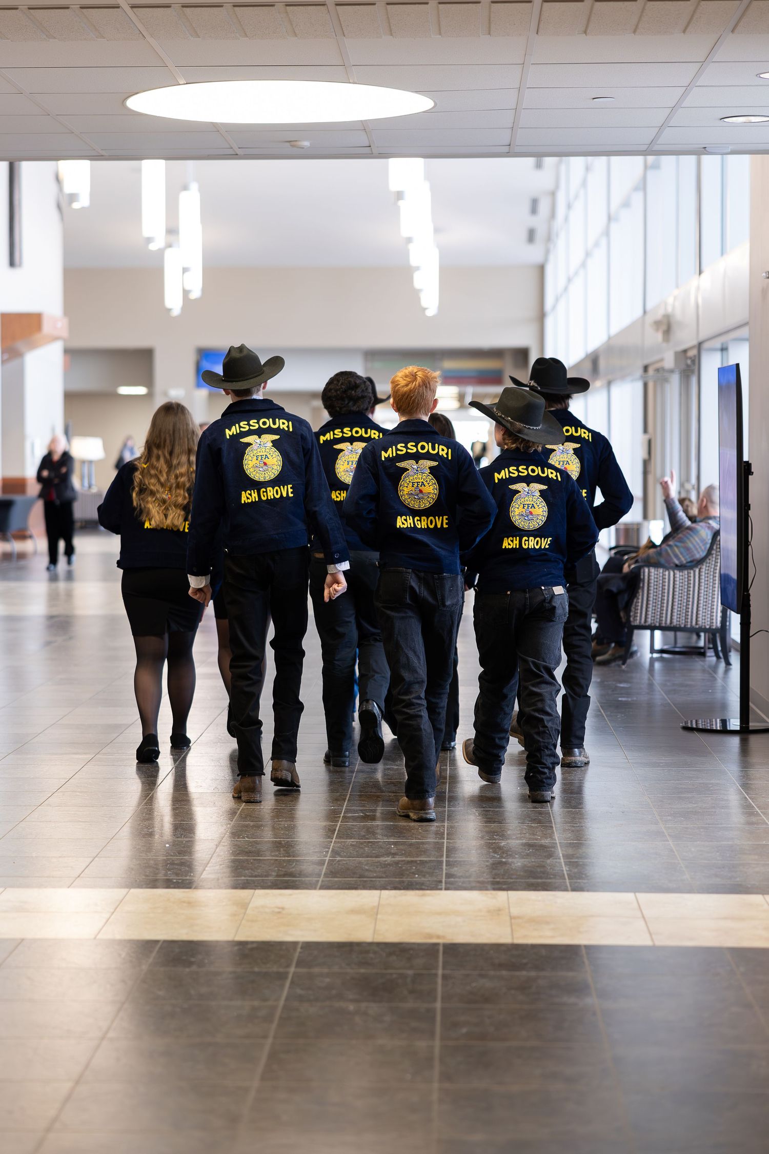 Group of FFA members in blue jackets walking down a hallway.
