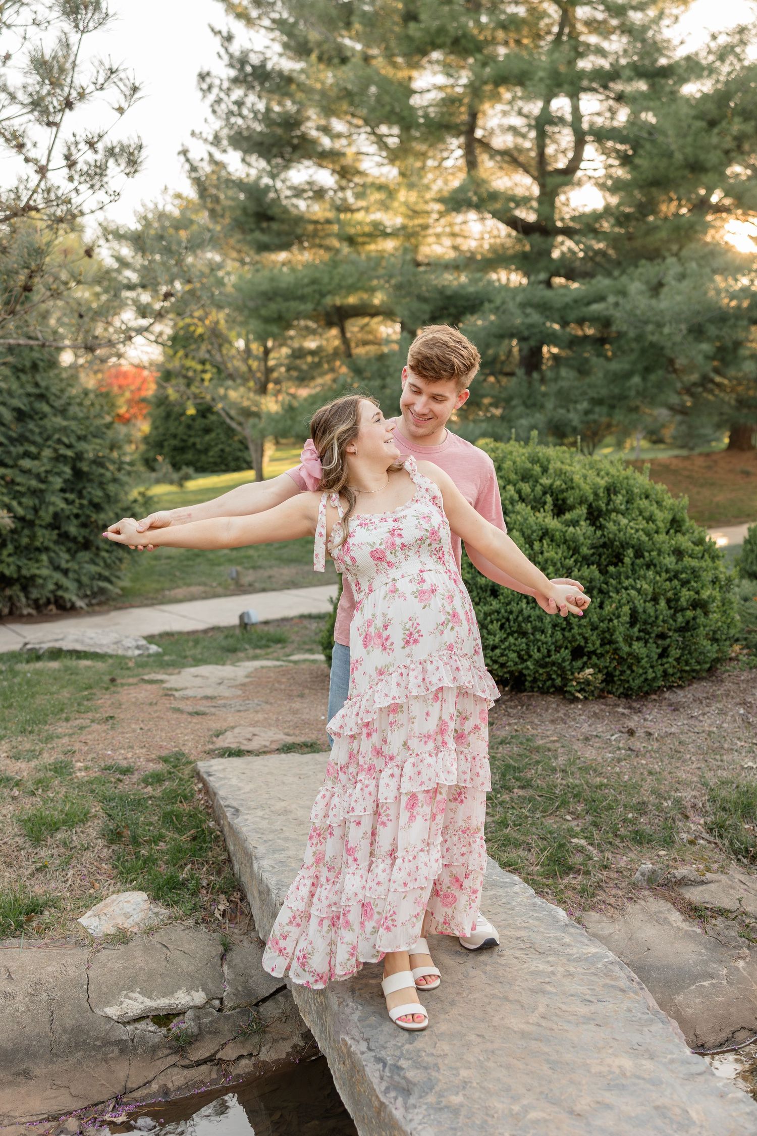 A romantic moment captured on a stone path surrounded by lush greenery and trees.