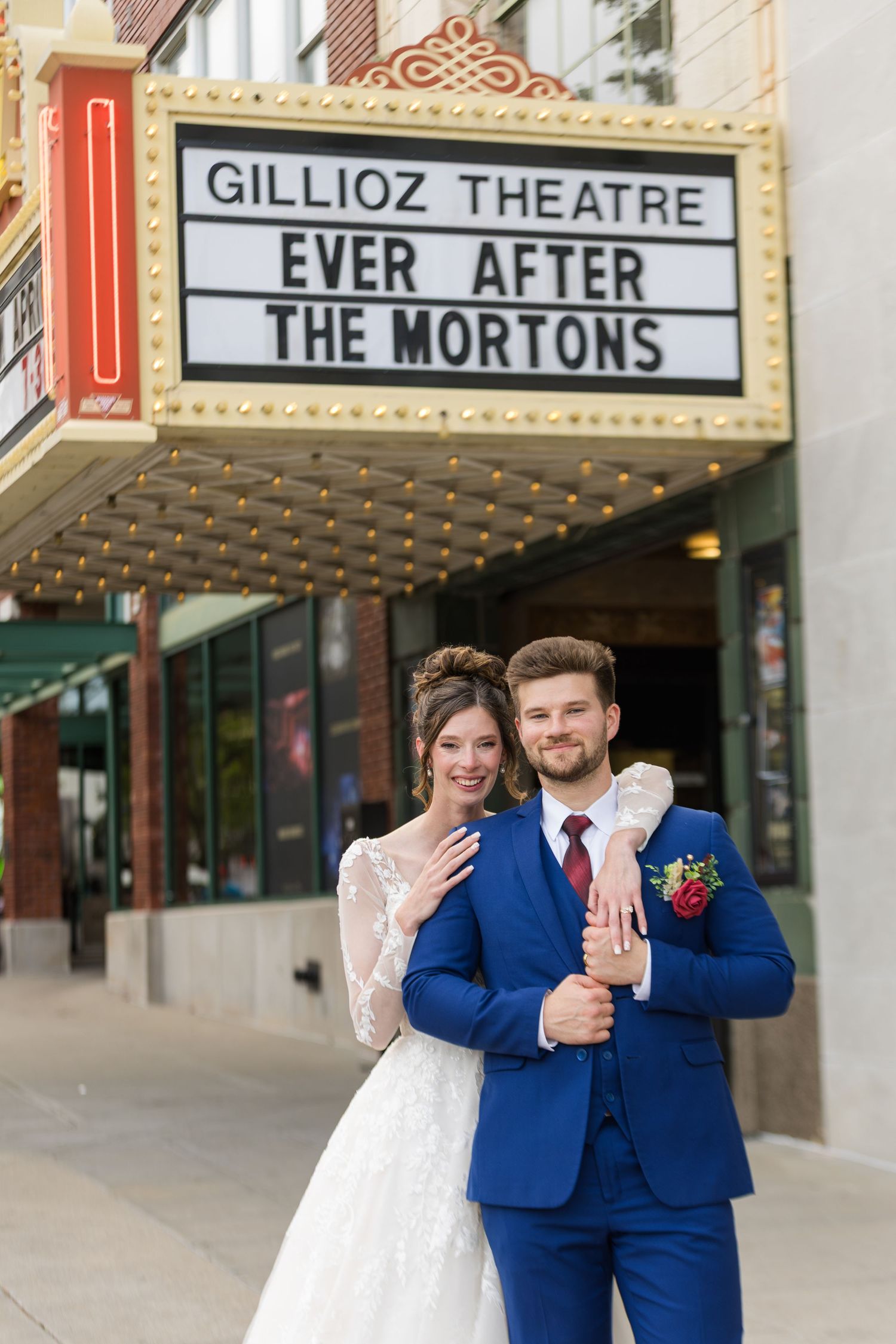 Bride and groom pose under Gillioz Theatre marquee reading Ever After The Mortons after wedding.
