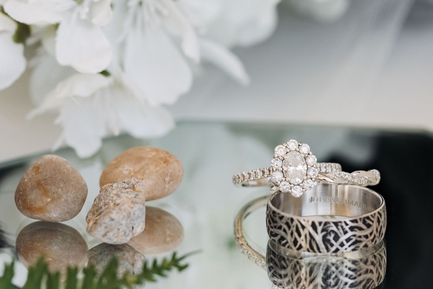Diamond engagement ring and wedding band photographed with white flowers and decorative details.