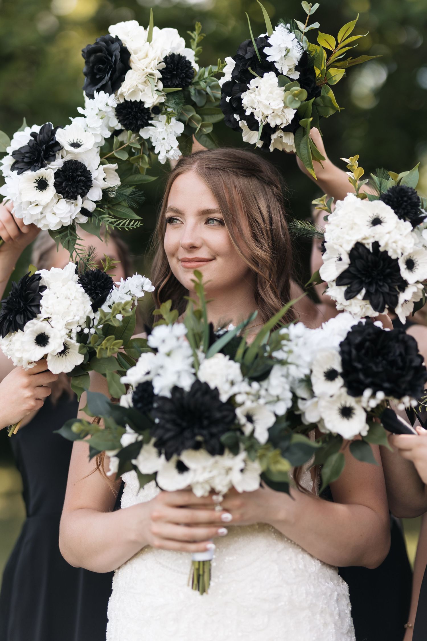 Bride surrounded by striking black and white floral bouquets in an artistic wedding photo.