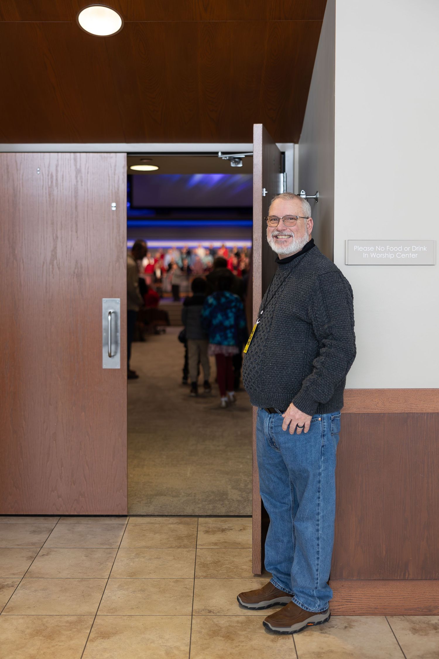 Staff member standing by doorway entrance during indoor event.