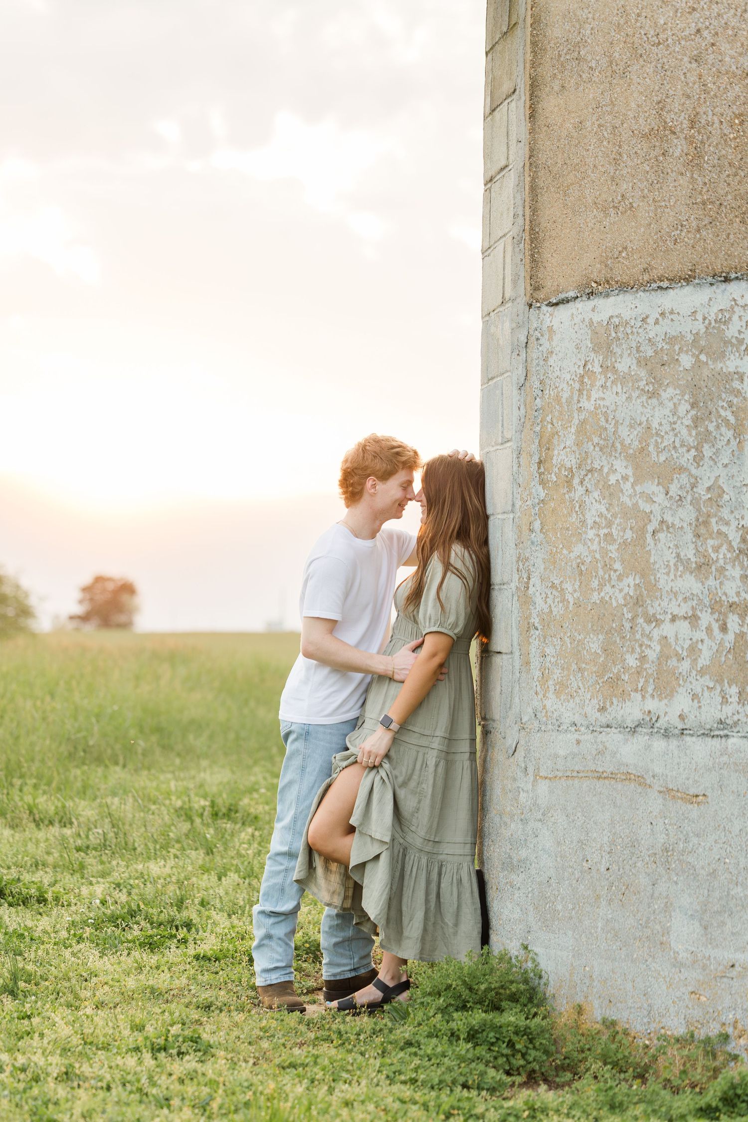 A romantic outdoor photo sequence showing a couple embracing against a rustic concrete wall at sunset.