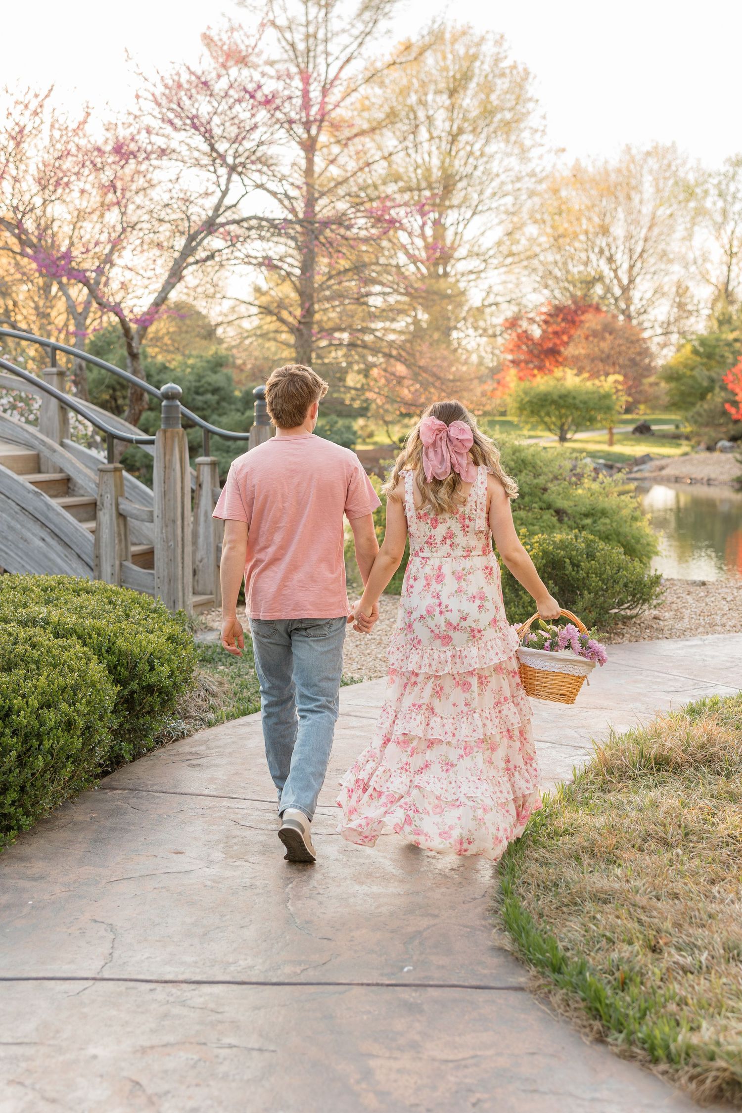 A couple strolls along a garden path next to a pond on a beautiful autumn day.
