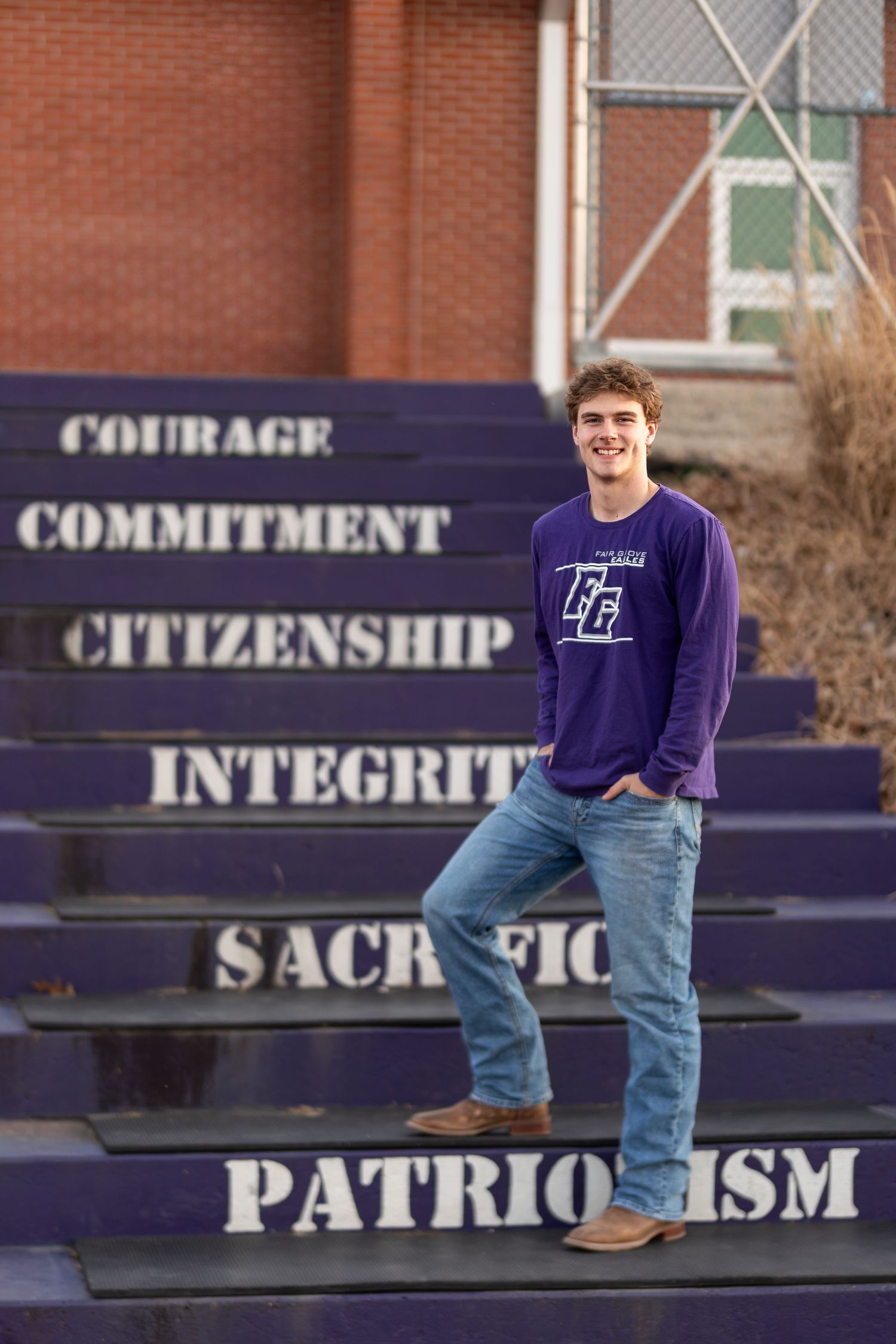 Purple school spirit text on concrete steps with student in matching sweatshirt.