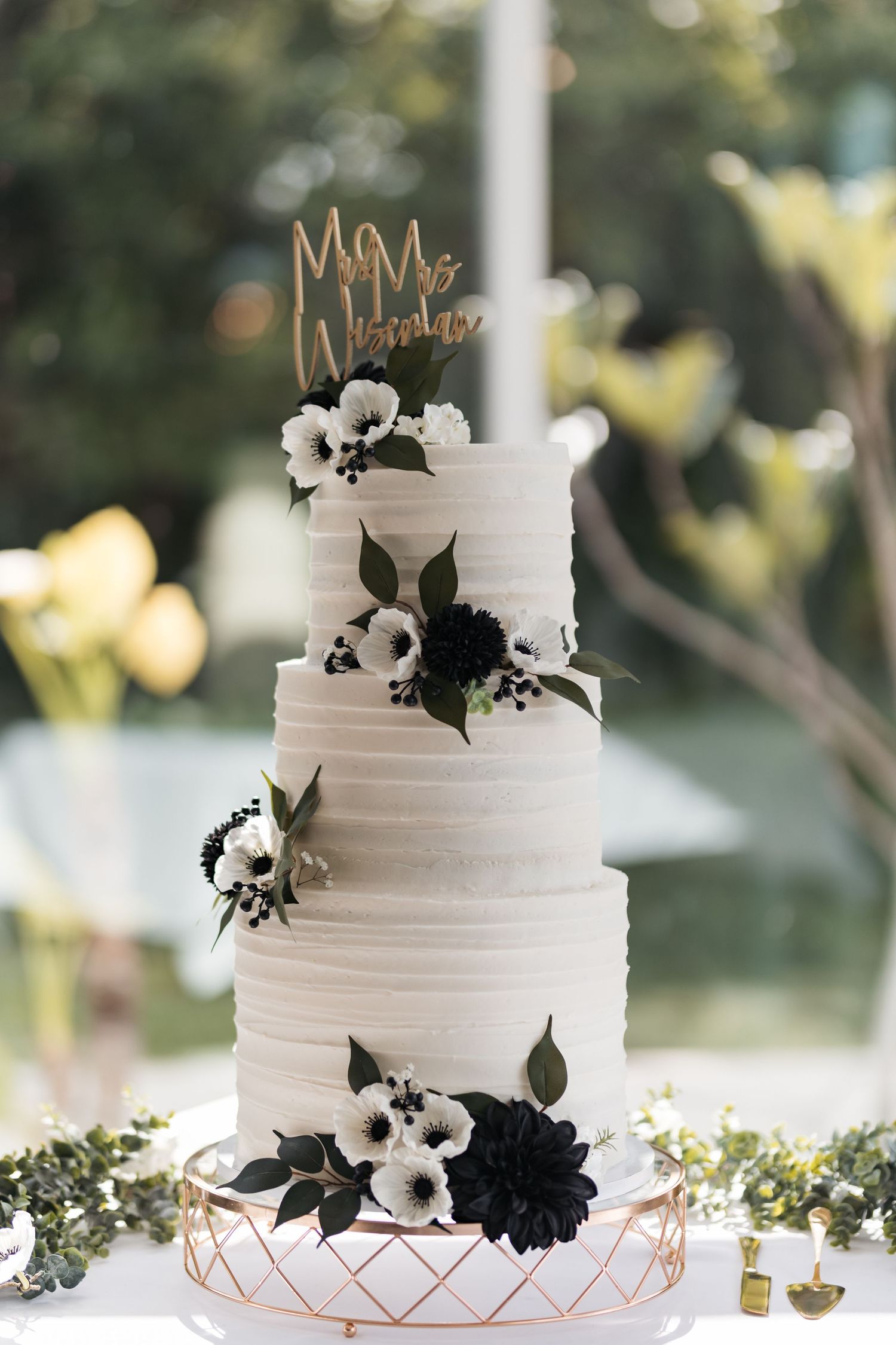 Elegant white wedding cake decorated with black and white anemone flowers and gold 