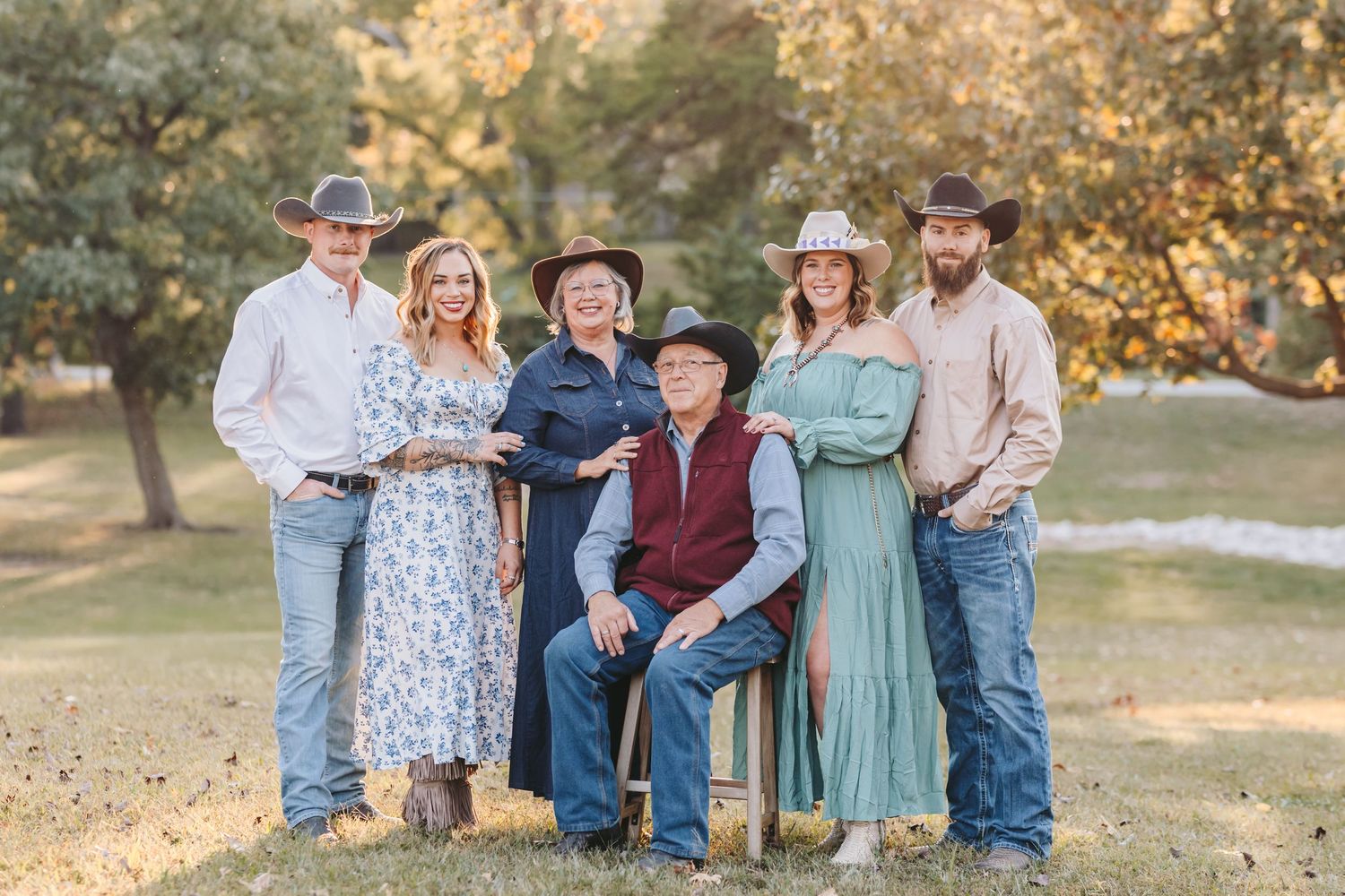Family members in western attire pose together outdoors with rustic wooden furniture.