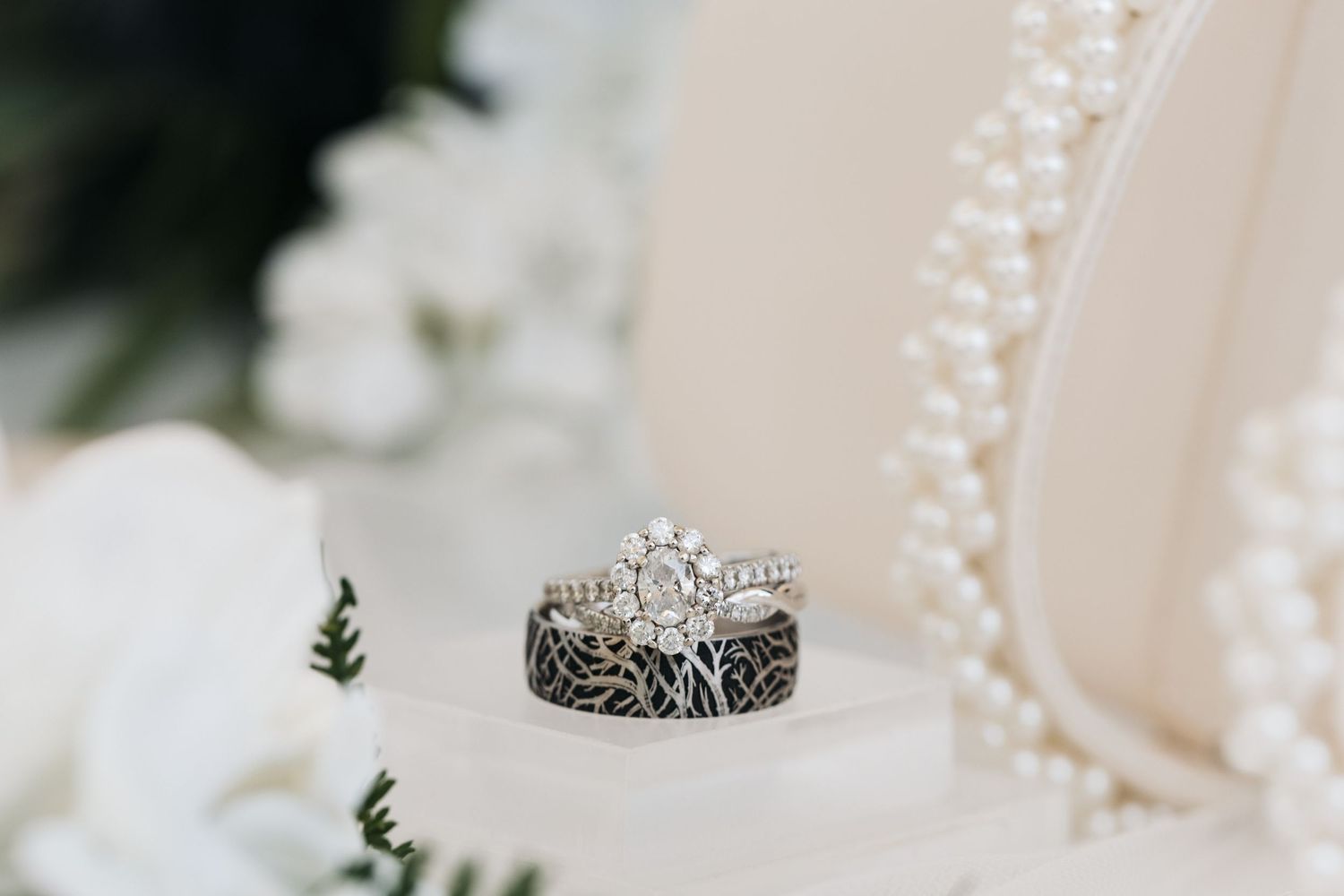A detailed closeup of an ornate wedding ring set displayed on white petals.