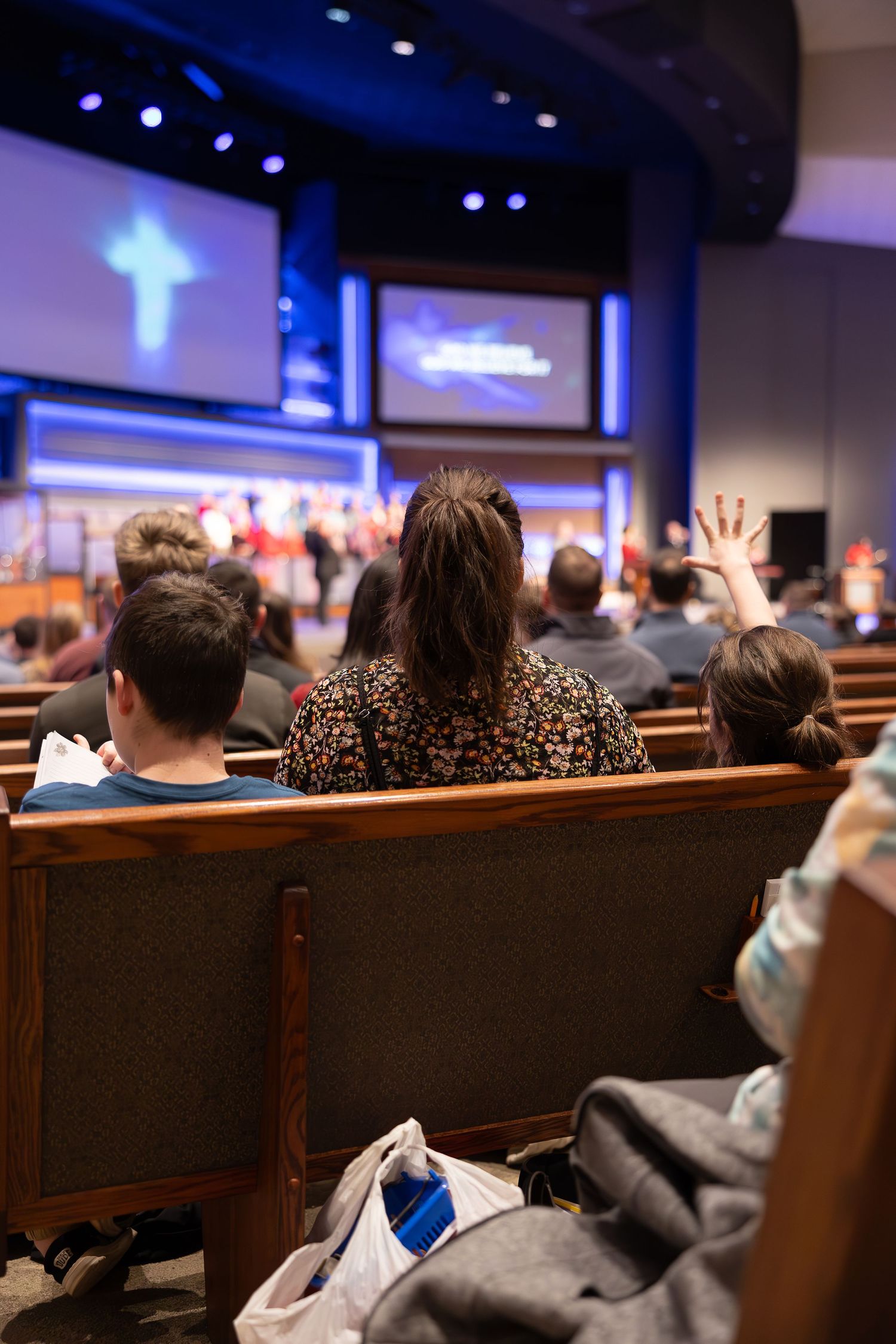People attending church service with hands raised during worship.