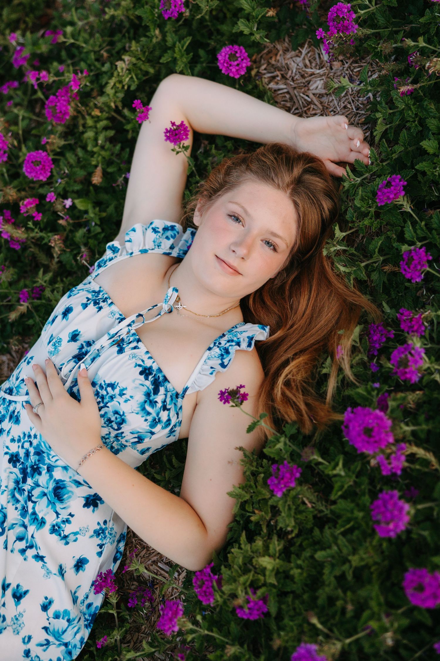 A blue and white floral dress contrasts with vibrant purple flowers in a garden setting.