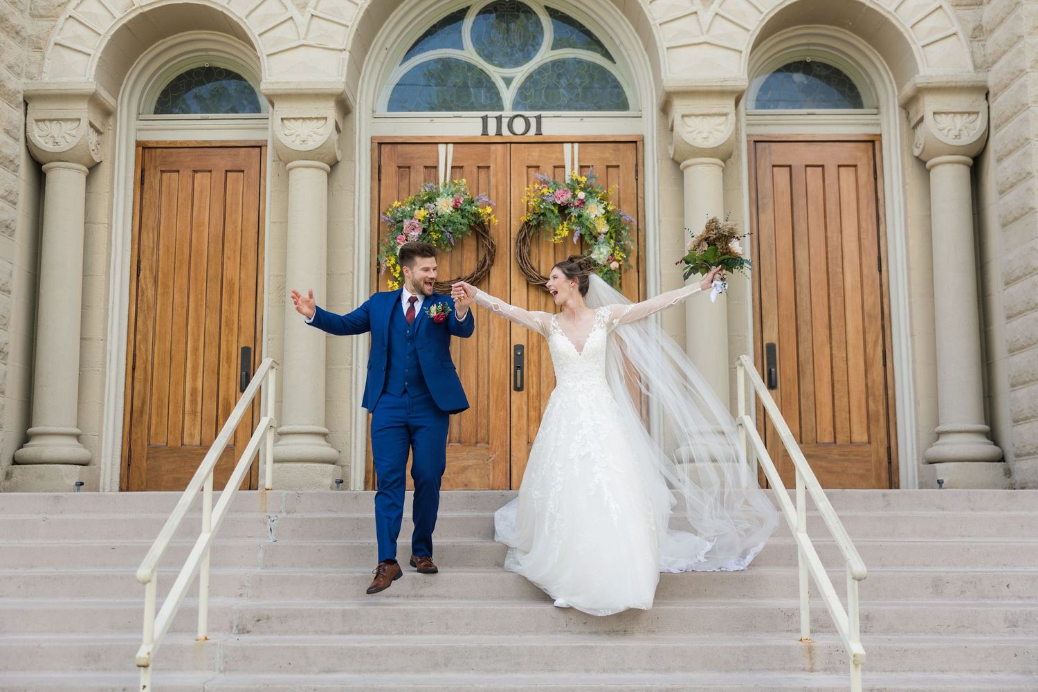Joyful newlyweds celebrate on steps of historic church building number 1101 after wedding ceremony.