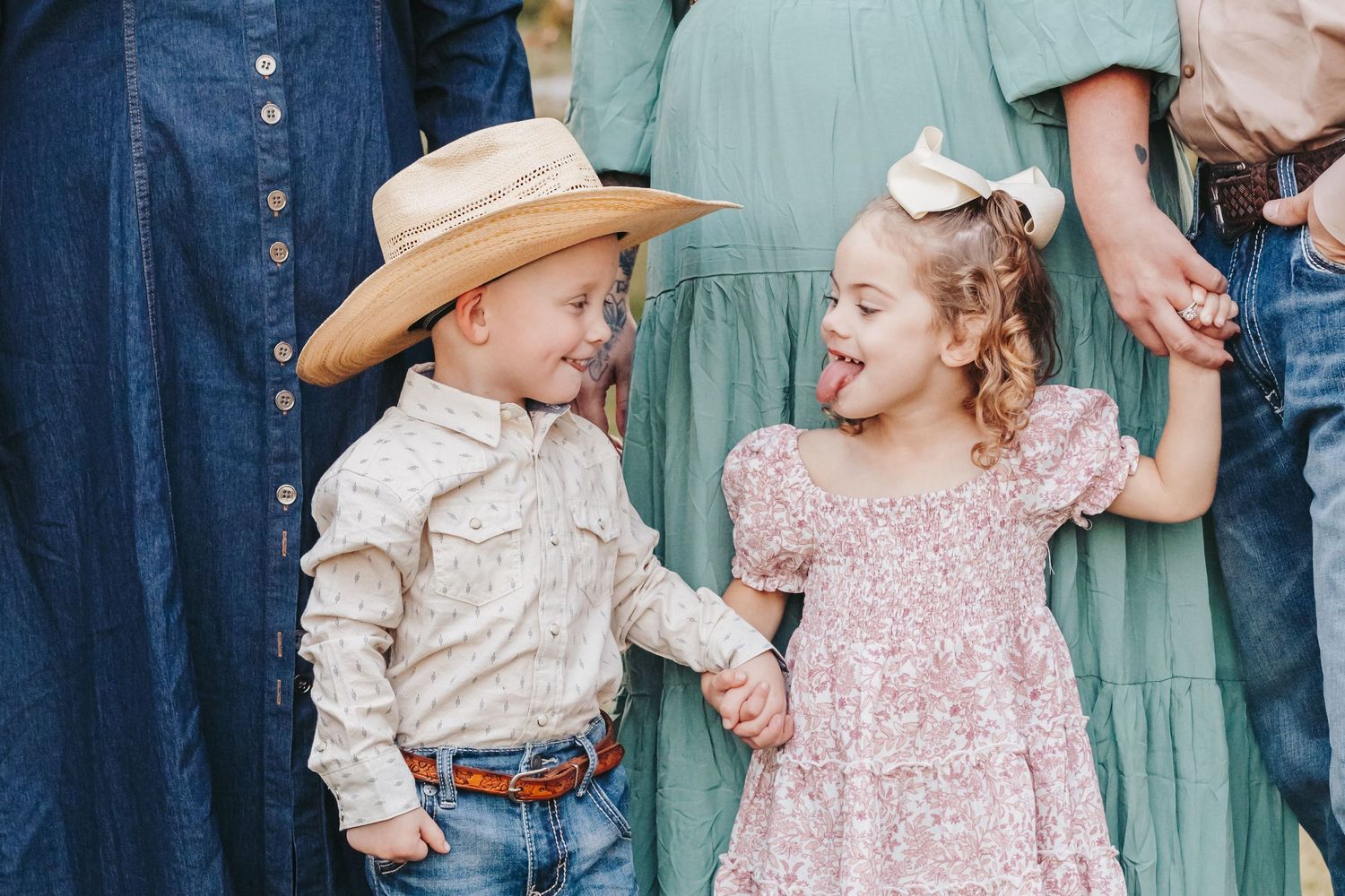 Two children in western attire share a playful moment during a family photo session.