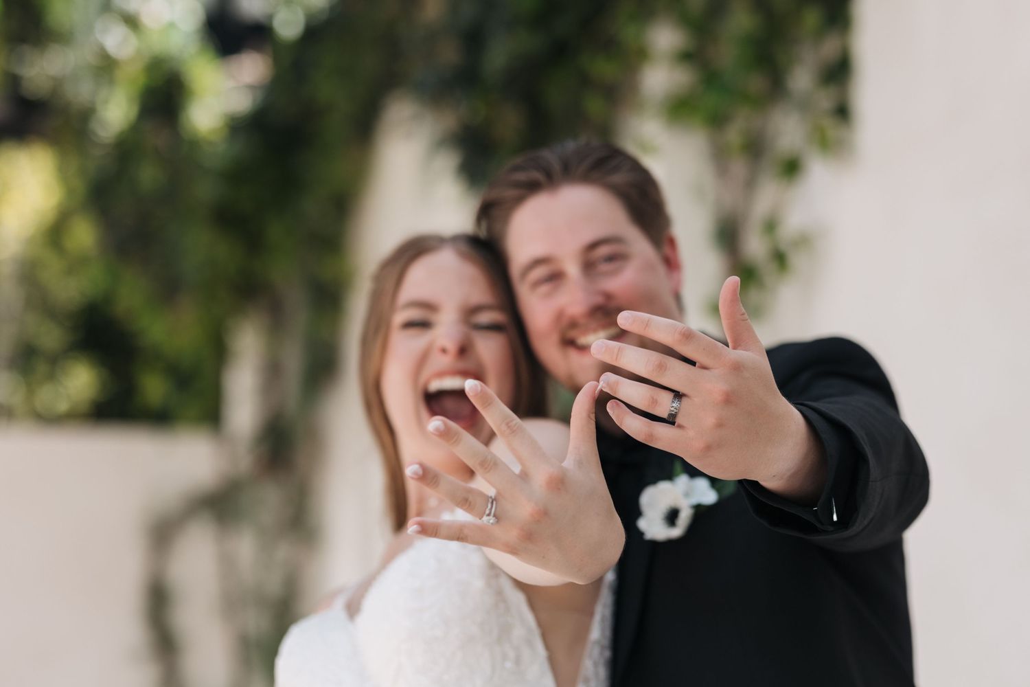 Candid moment of newlyweds showing off their wedding rings with excitement.