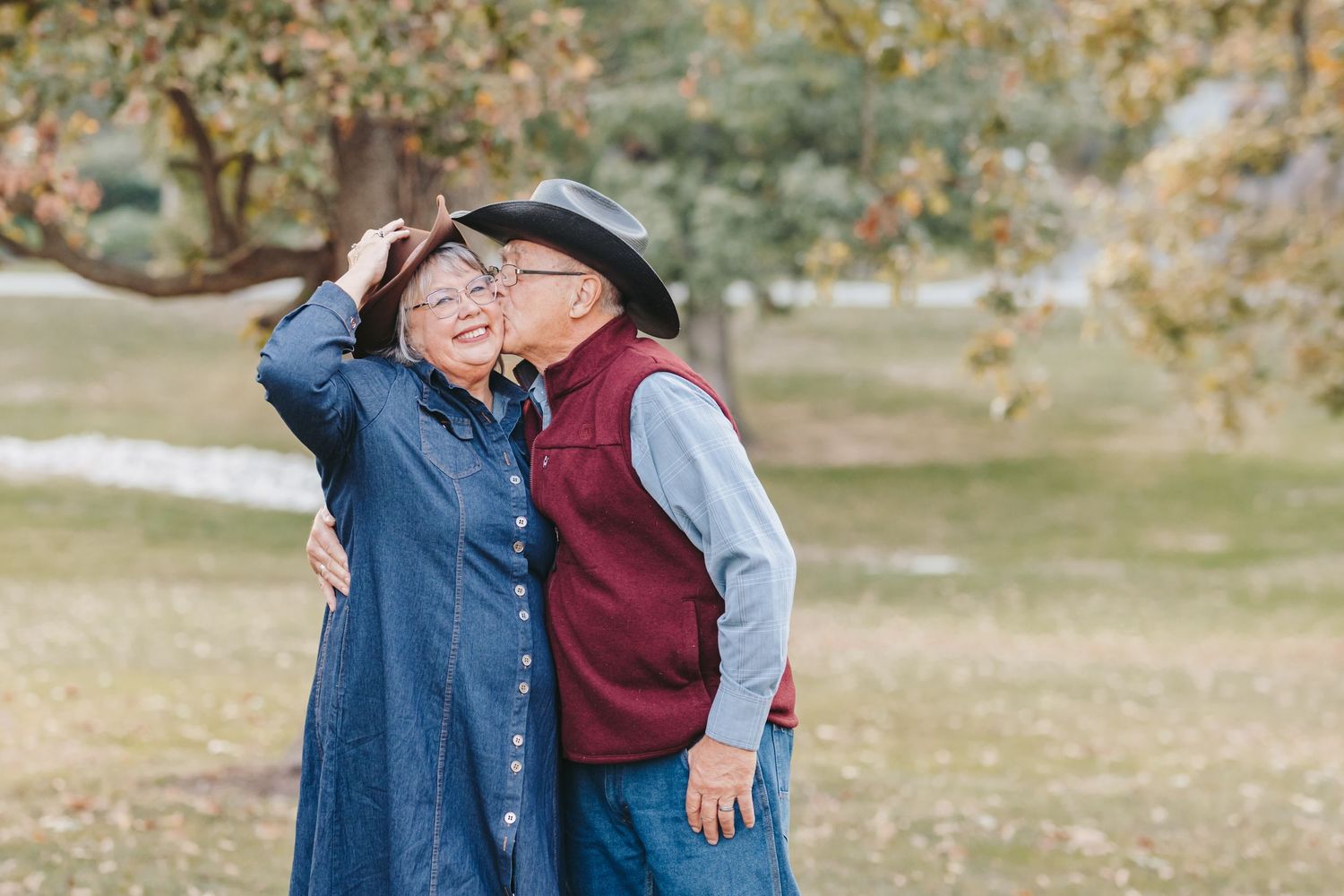 Couple in casual western wear share a tender moment outdoors.