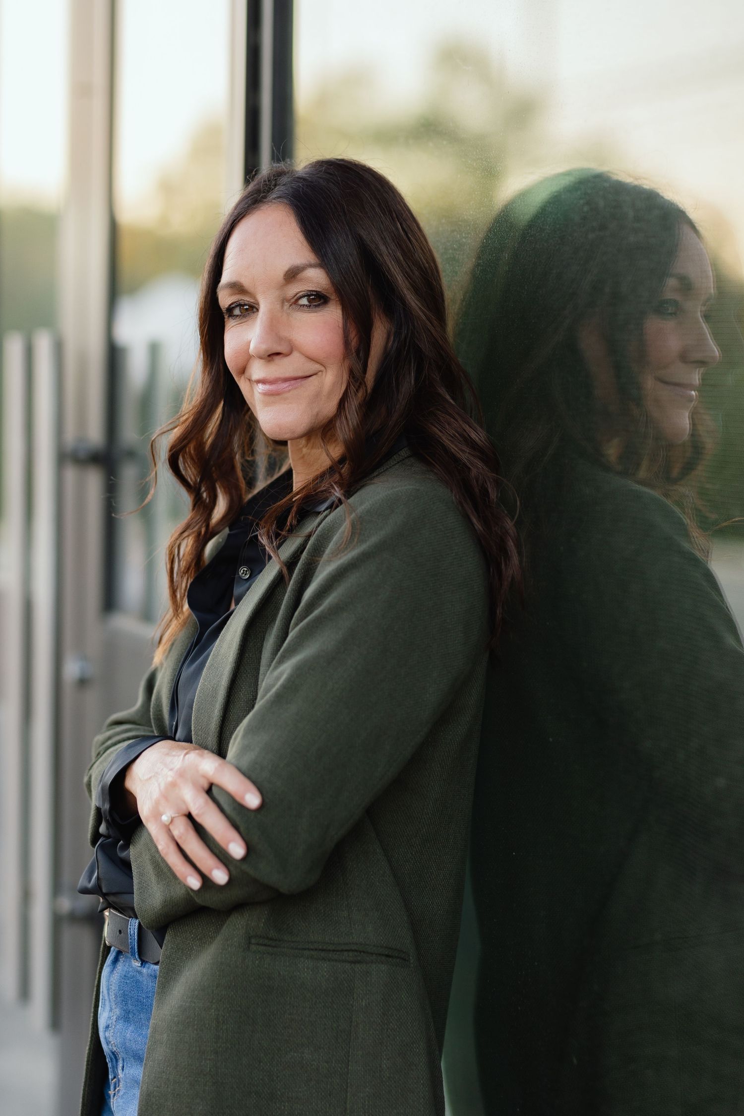 Business casual portrait against reflective window showing professional style and confidence.