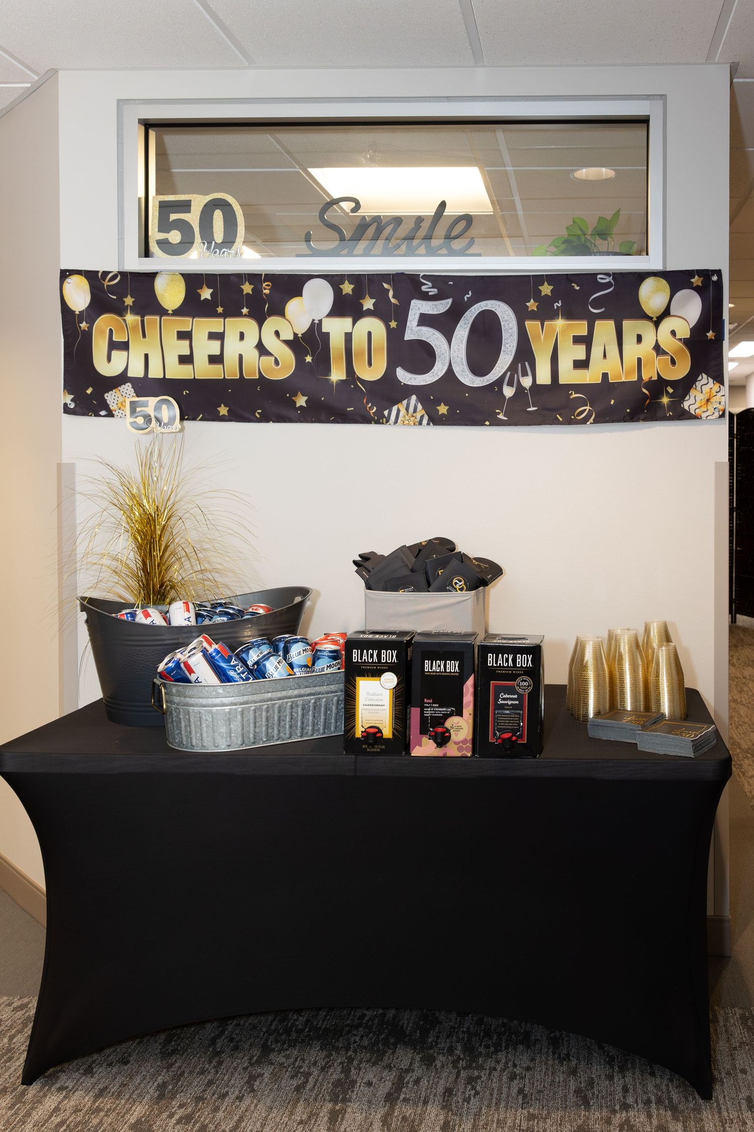 Celebratory display table with 'Cheers to 50 Years' banner and drinks setup.