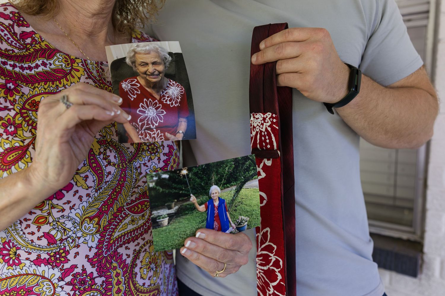 Two people hold cherished photographs and a decorated tie, preserving memories of a loved one at a wedding.