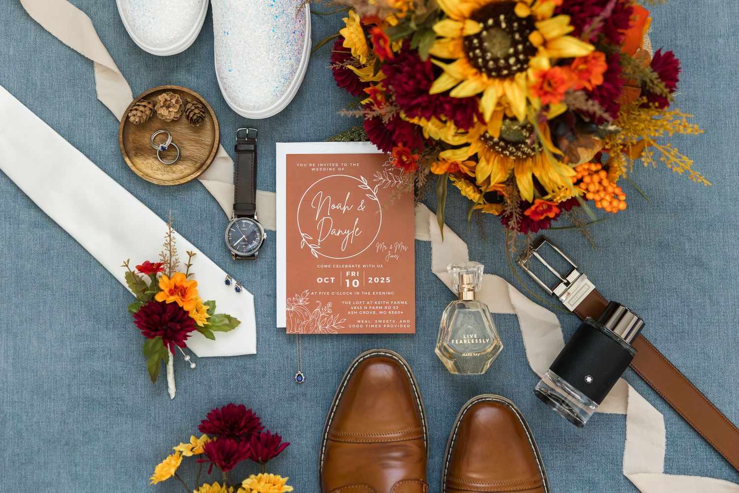 Wedding table decor with rustic brown leather shoes, sunflowers, and wine glasses on a blue-gray surface.