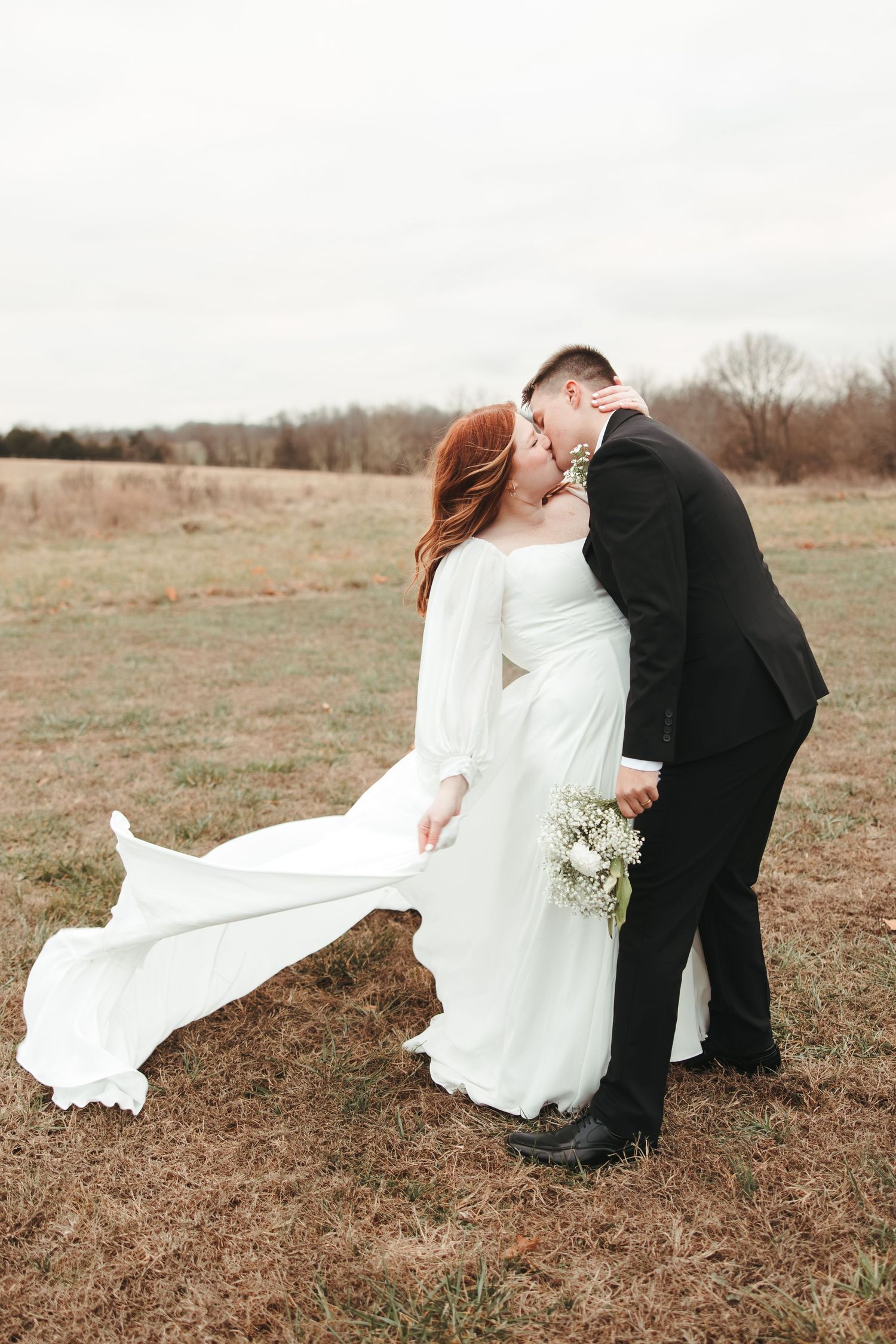 Romantic wedding portrait in rustic field with flowing white dress.