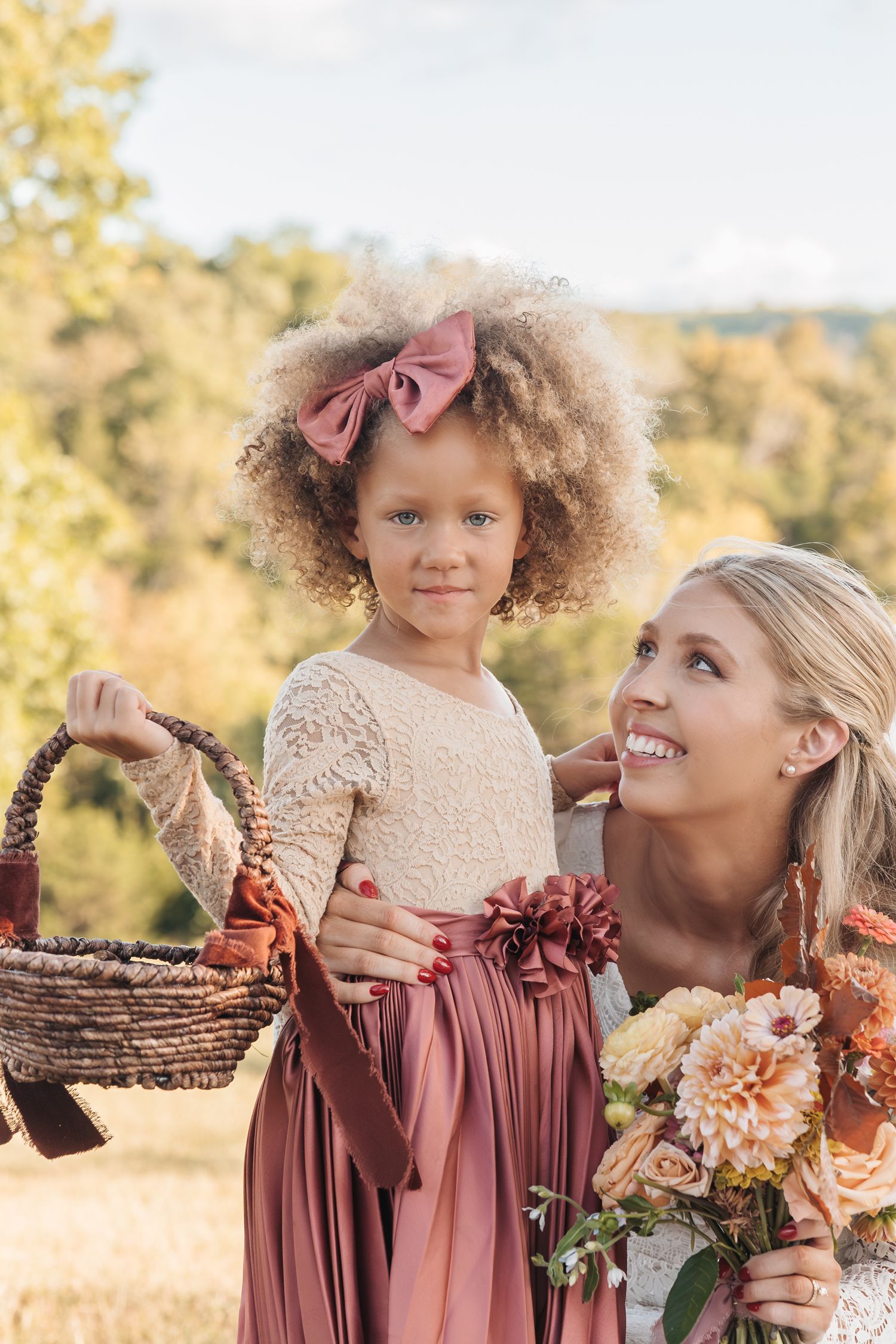 Autumn wedding portrait featuring matching mauve dresses and a beautiful floral bouquet in warm sunset lighting.