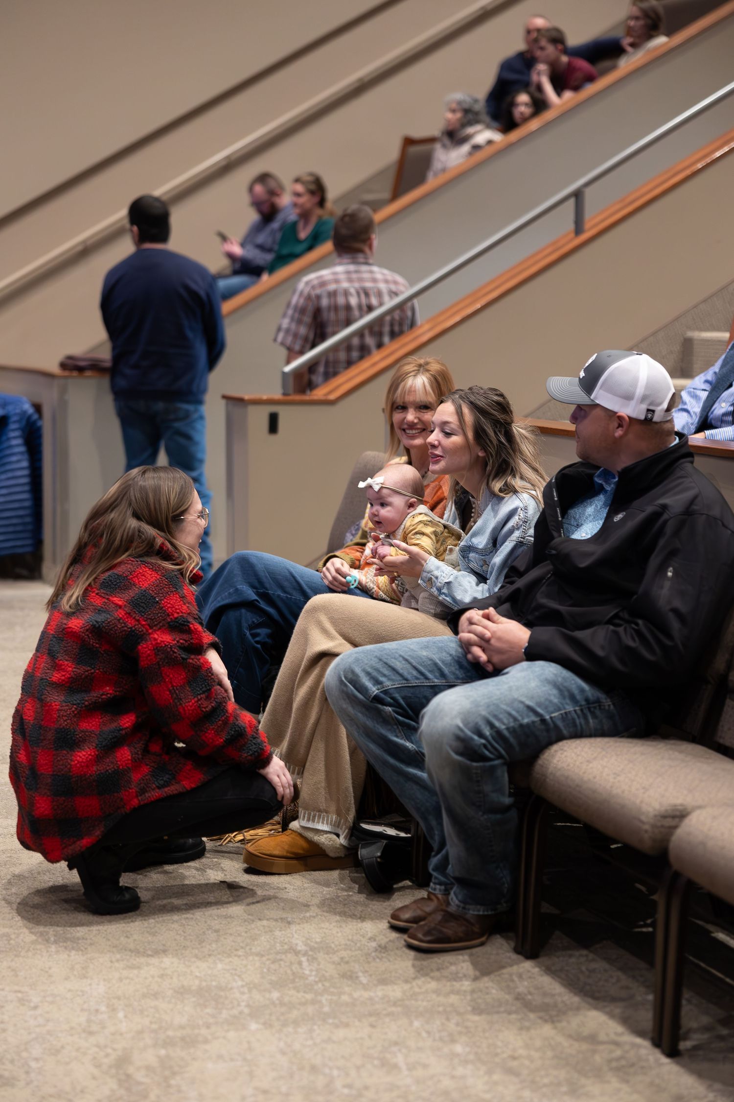 Group of people sitting and chatting on stairs in an indoor gathering space.