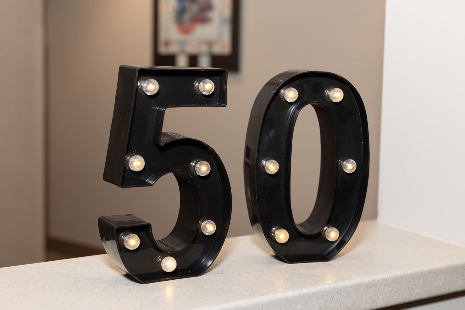 Black light-up number 50 display with illuminated bulbs on white surface.