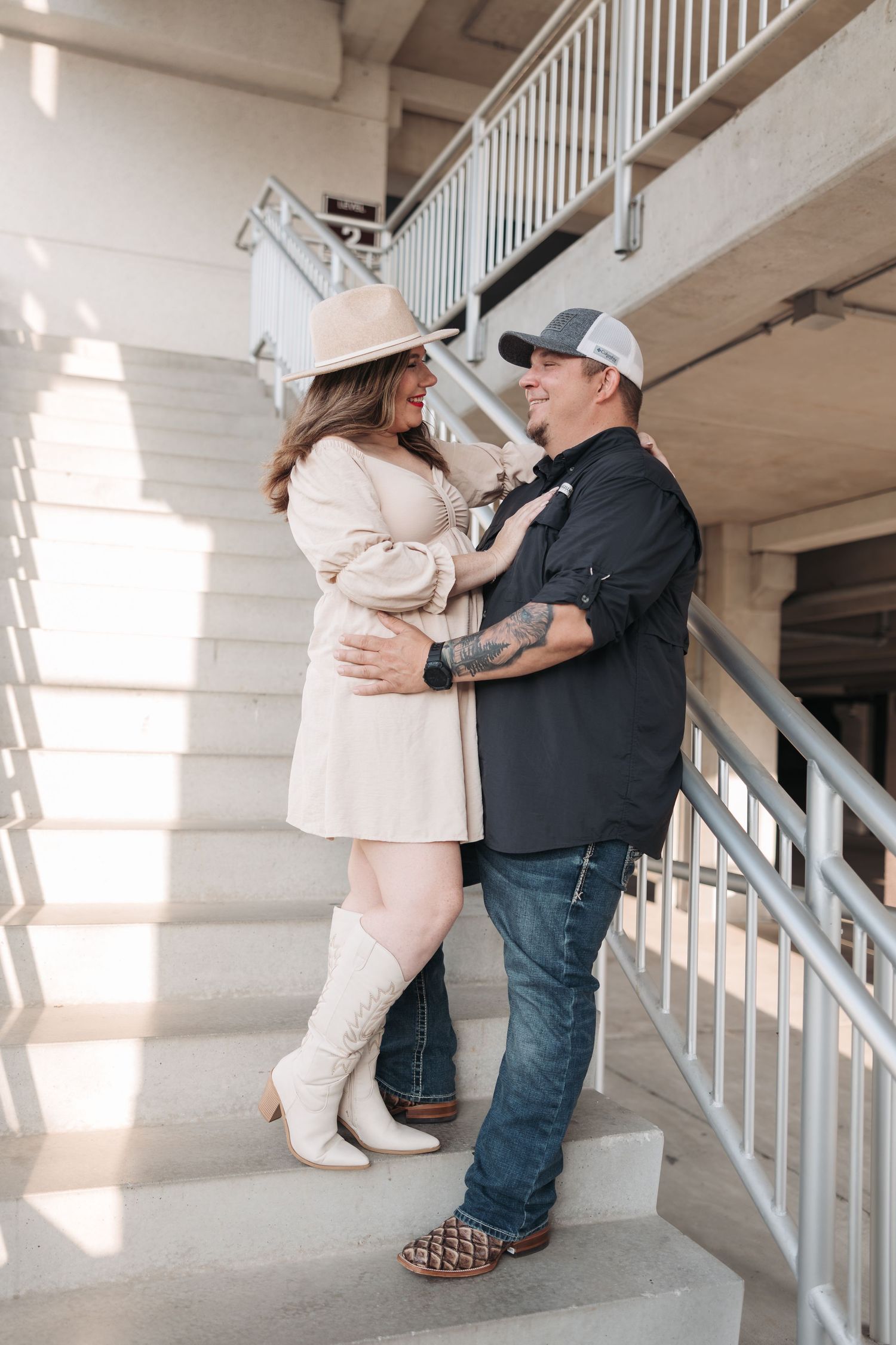 Couple in western attire posing on stairs with white railings.