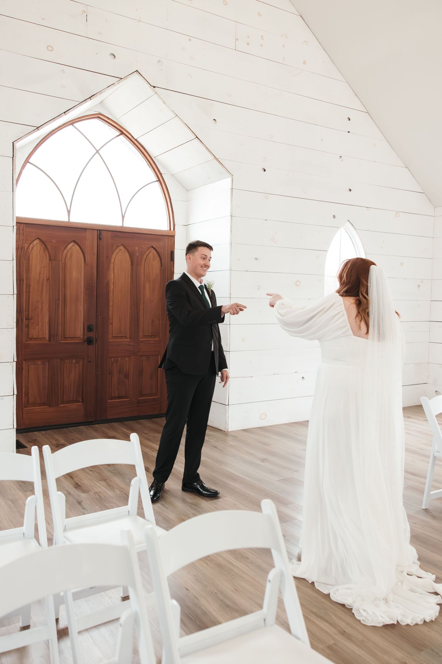 Couple sharing a moment in bright white chapel with arched wooden door.