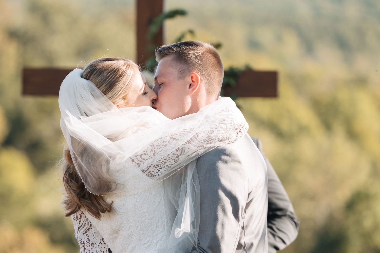 A romantic embrace between newlyweds with a scenic mountain backdrop.