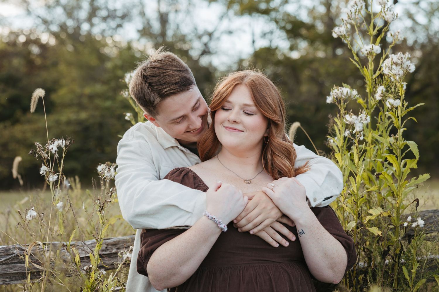 A romantic outdoor couples photoshoot featuring embracing figures among wildflowers at sunset.