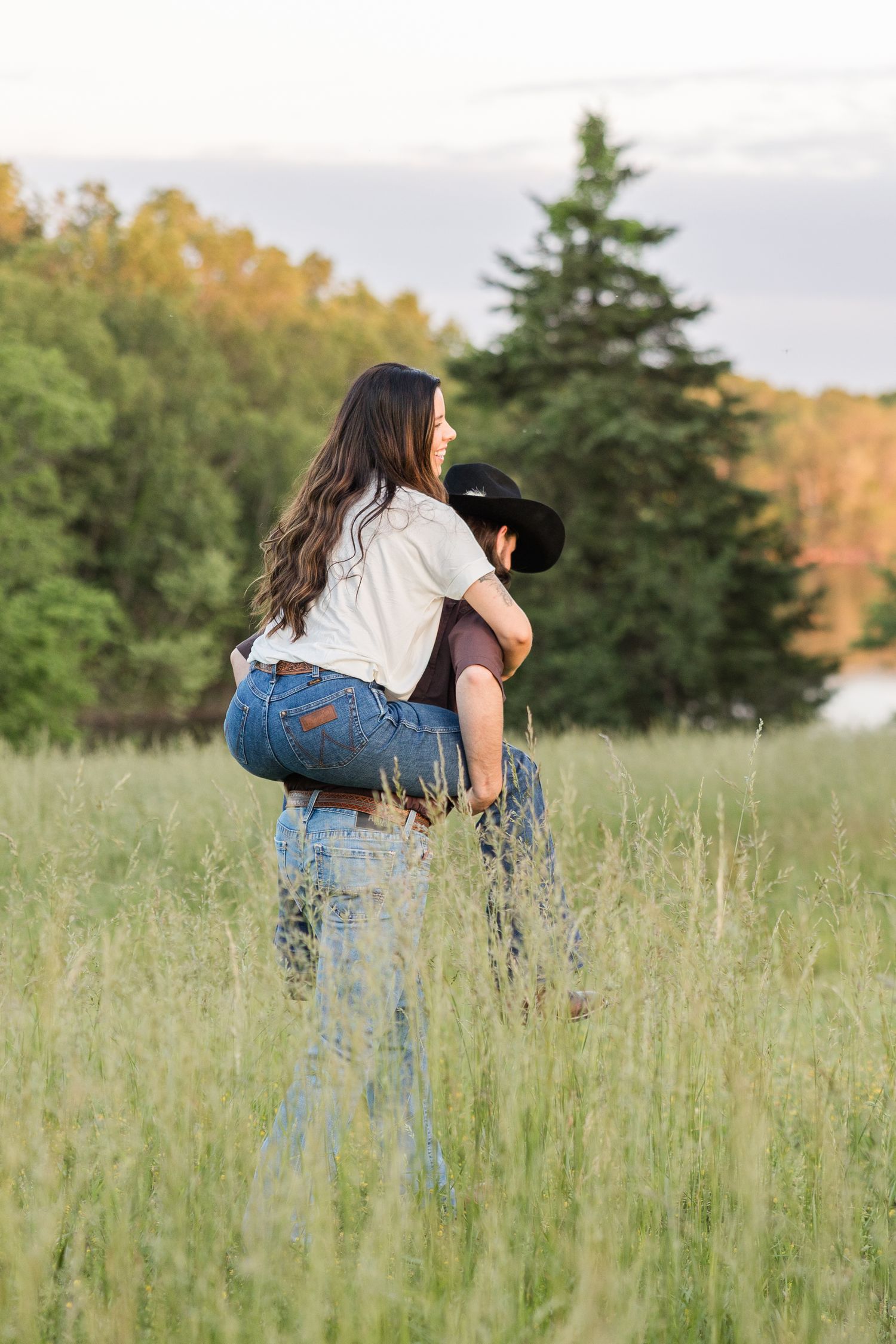 Photographer crouching in tall grass during sunset to capture photos in a meadow.