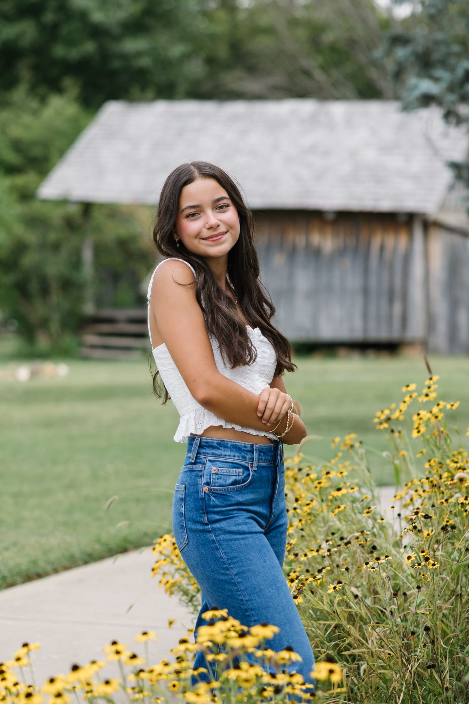 A series of casual poses near yellow wildflowers with a rustic barn in the background.