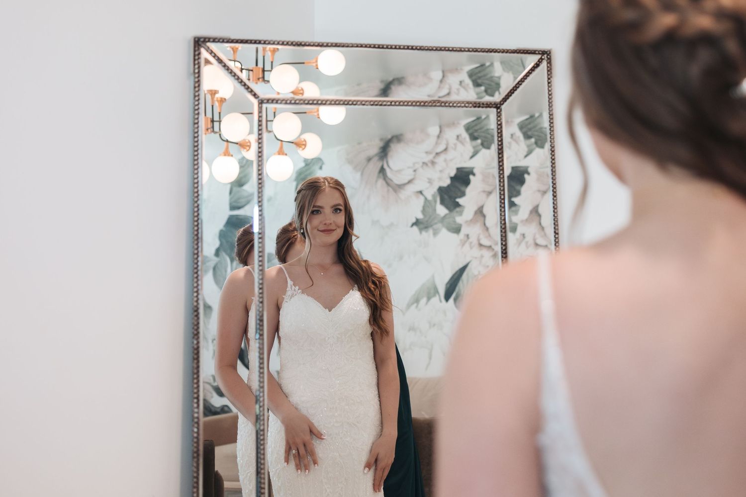 A white wedding dress is reflected in an ornate mirror with geometric details.