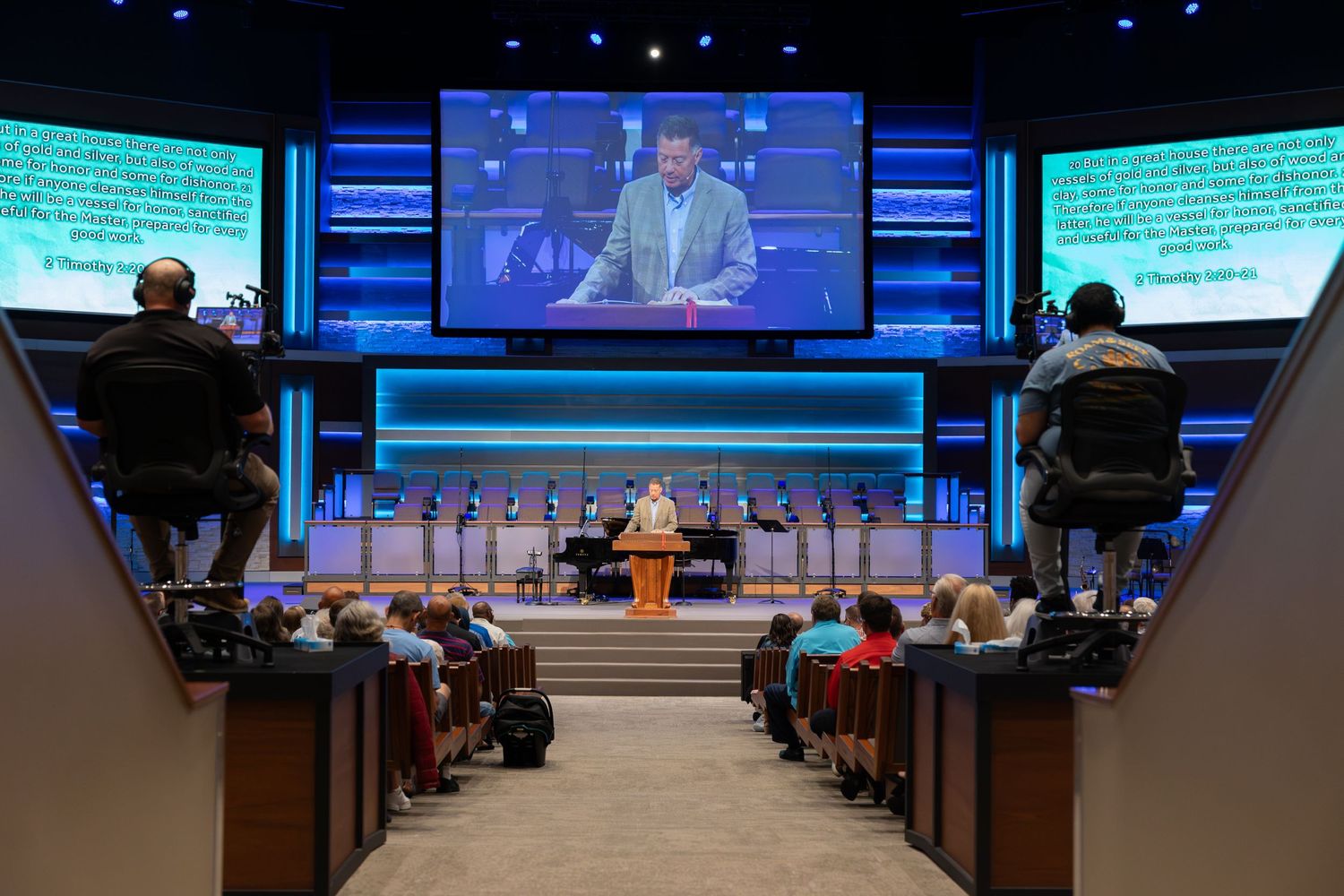 A wide view of a modern church sanctuary with video screens and blue stage lighting.