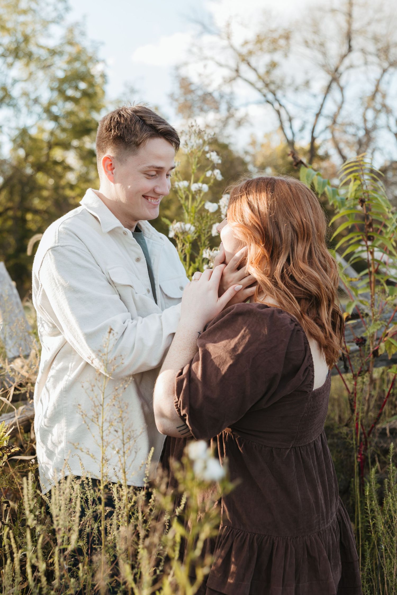 Gentle moment between a couple in casual attire amid wild summer flowers.