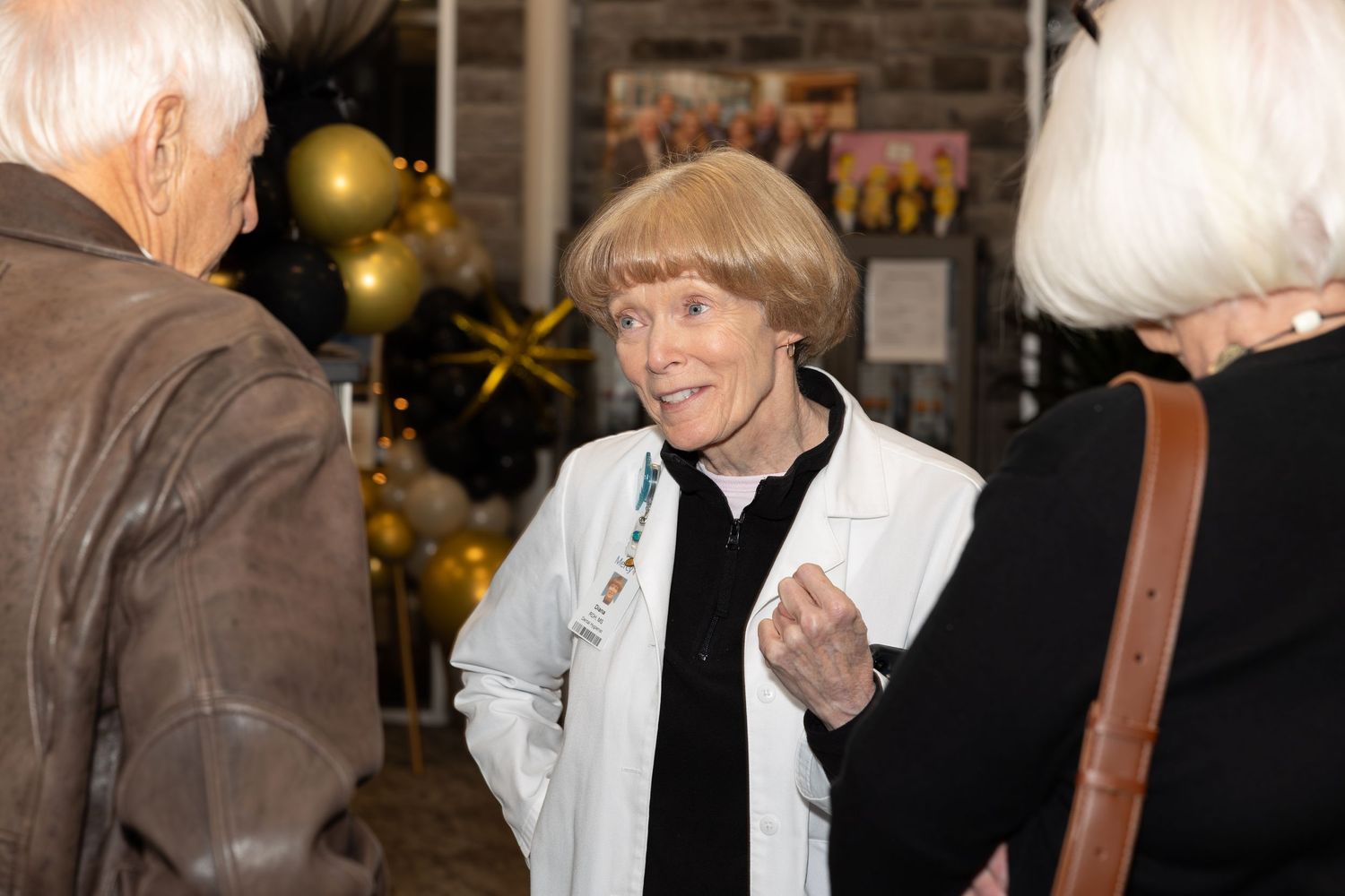 Social gathering with guests chatting near decorative gold and black balloons.