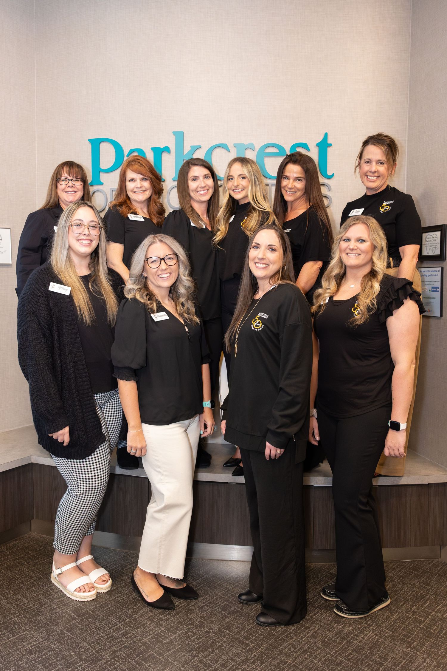 Staff members in black attire pose in front of Parkcrest office sign.