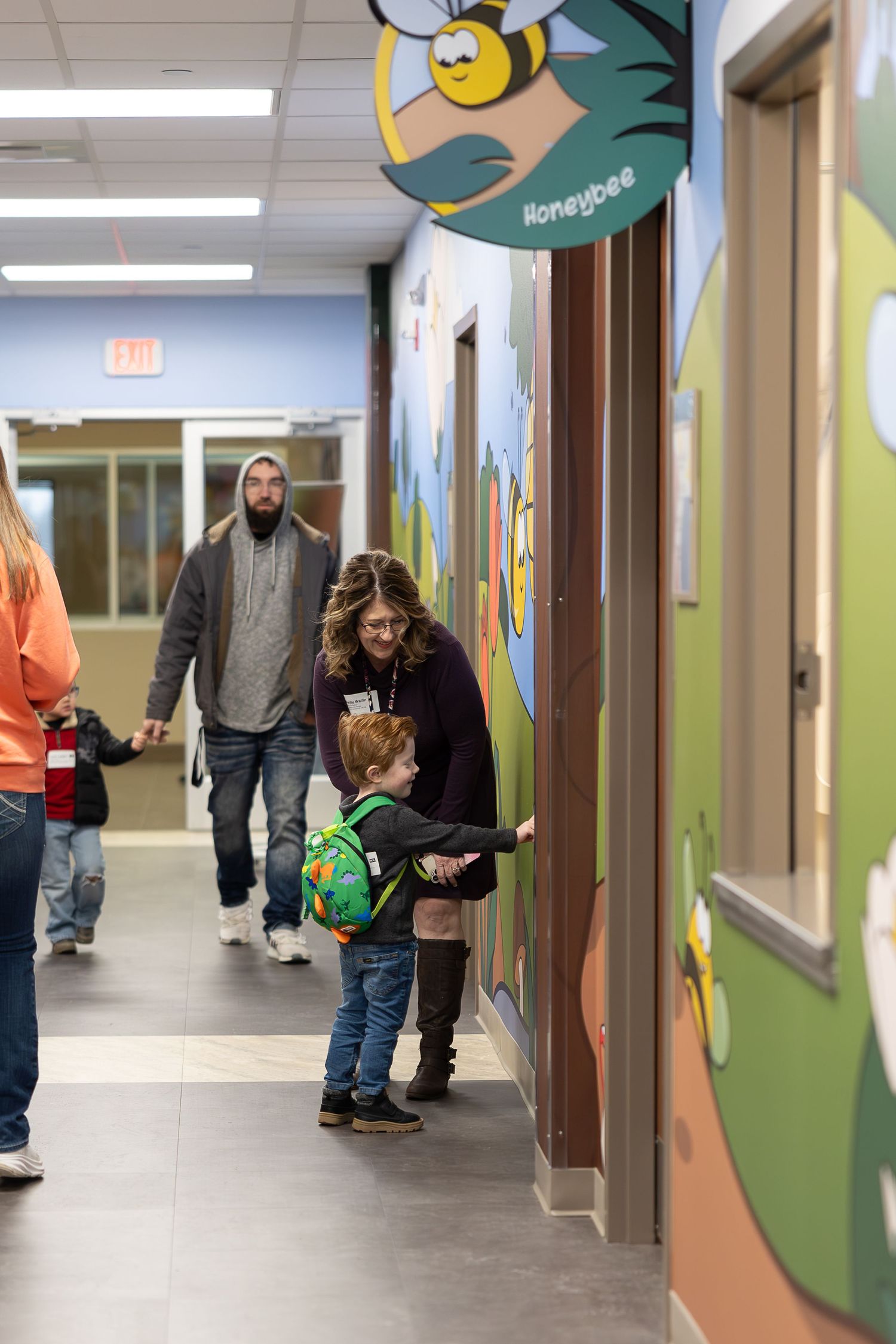 People walking through a decorated hallway with whimsical bee artwork on the walls.