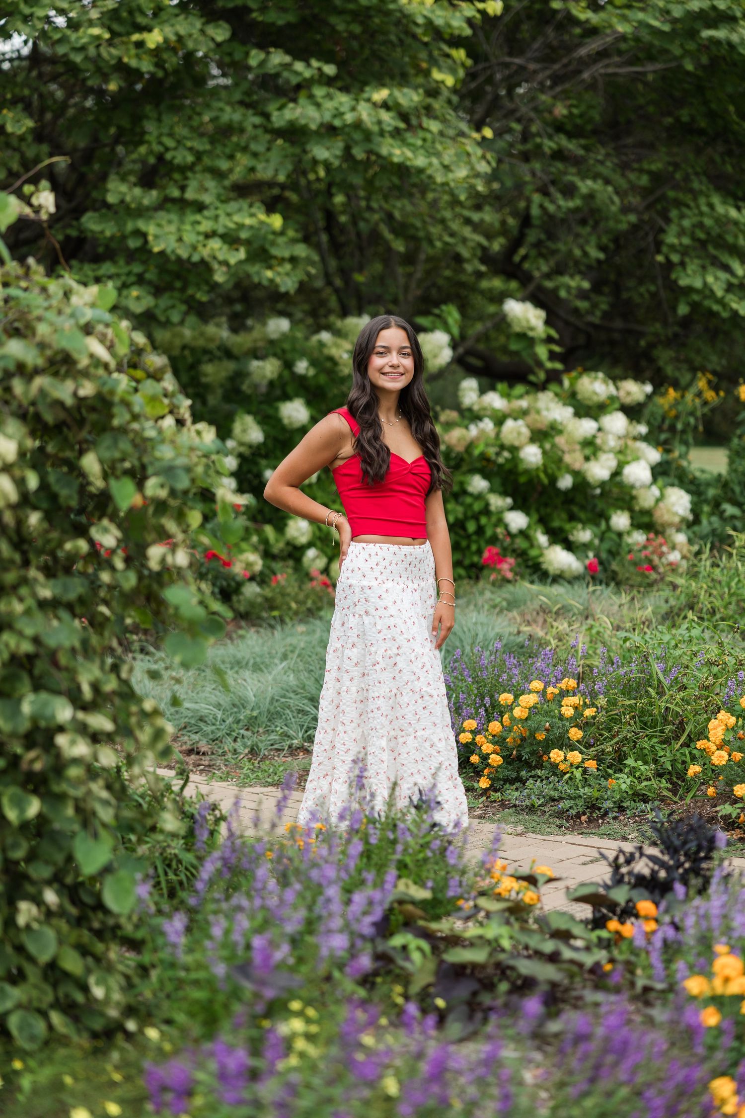 A summer garden blooms with roses, lavender, and colorful flowers along a stone pathway.