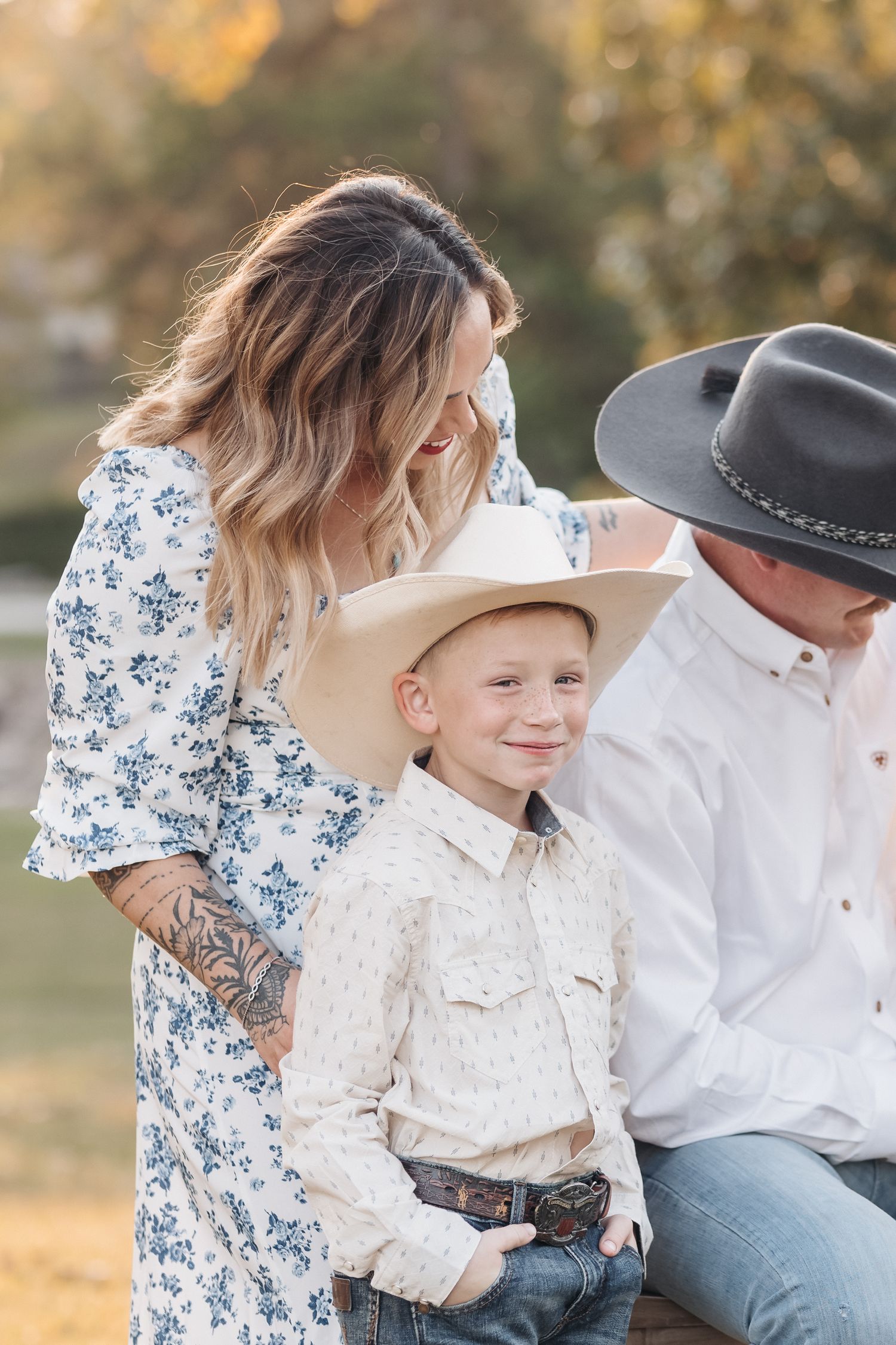 Family in western attire shares a tender moment during outdoor portrait session.