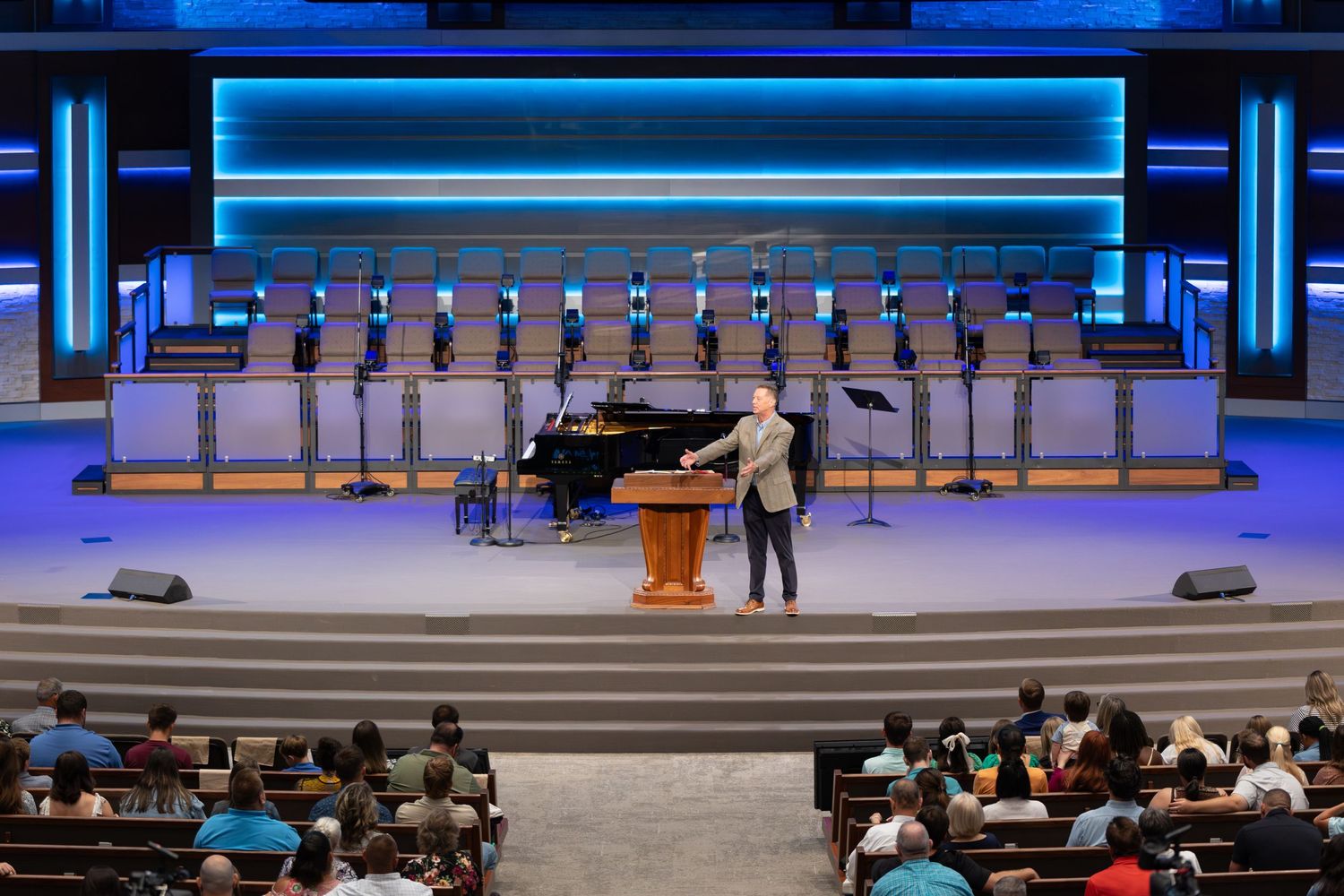 Interior view of a large church auditorium with stage setup featuring piano and choir risers.
