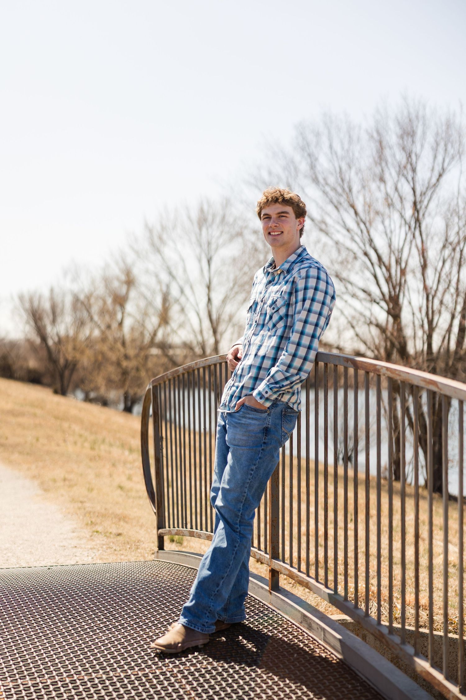 Casual portrait of person standing on metal bridge railing during winter.
